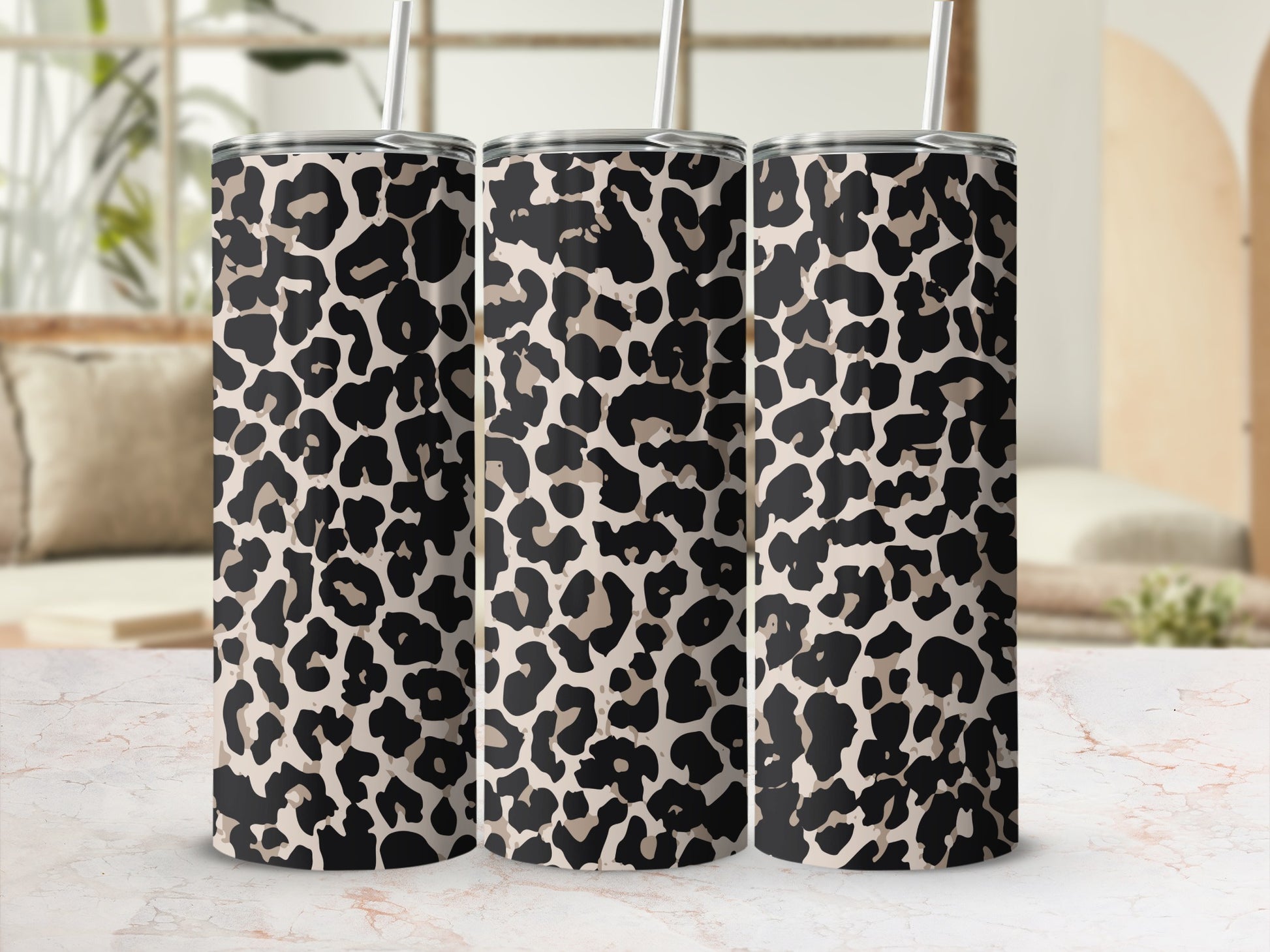 Three tumblers with a neutral leopard print and straws displayed in a row.