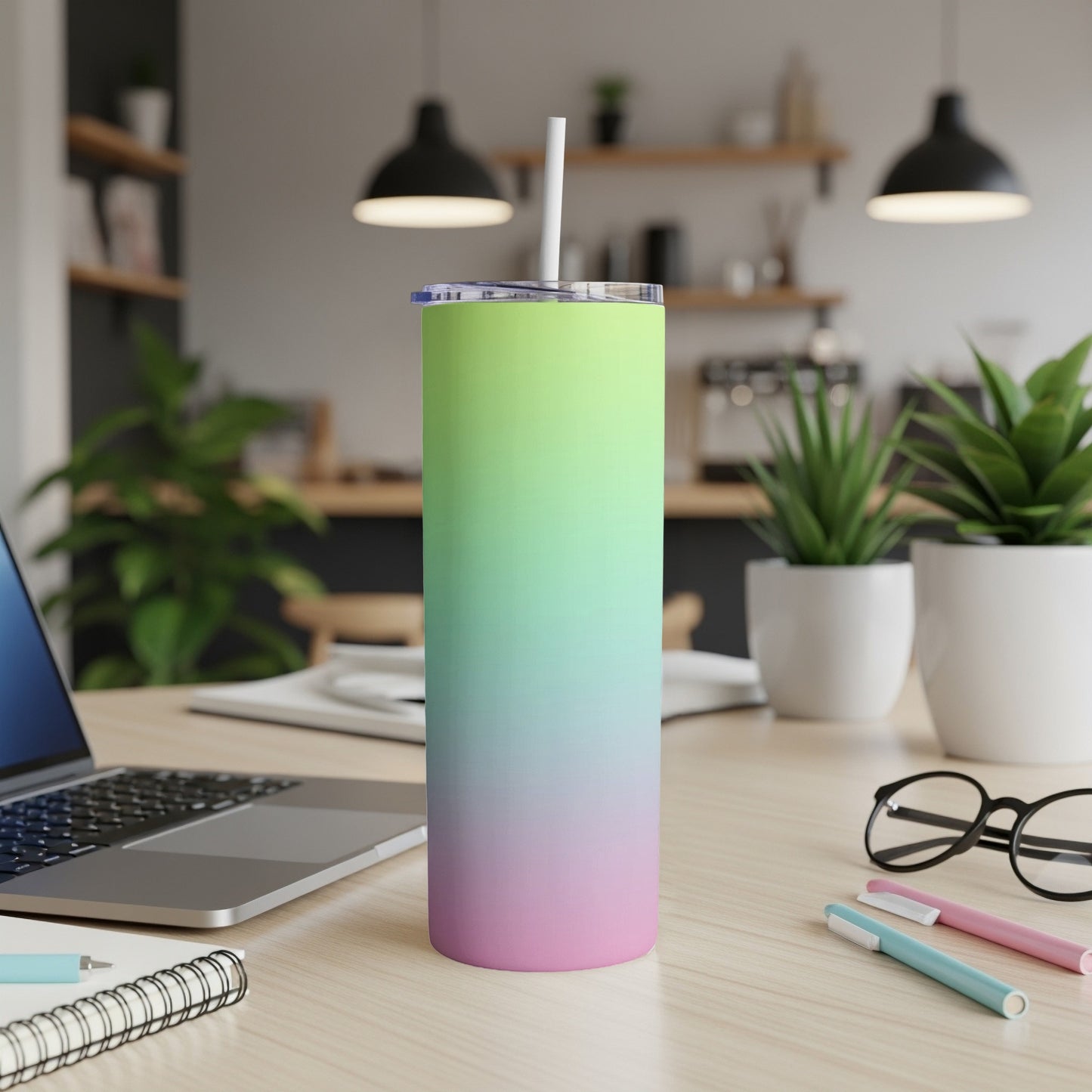 Gradient pink and green tumbler with straw on a desk.