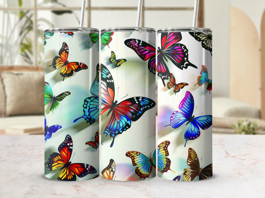 Three tumblers with colorful butterfly designs on a marbled surface.