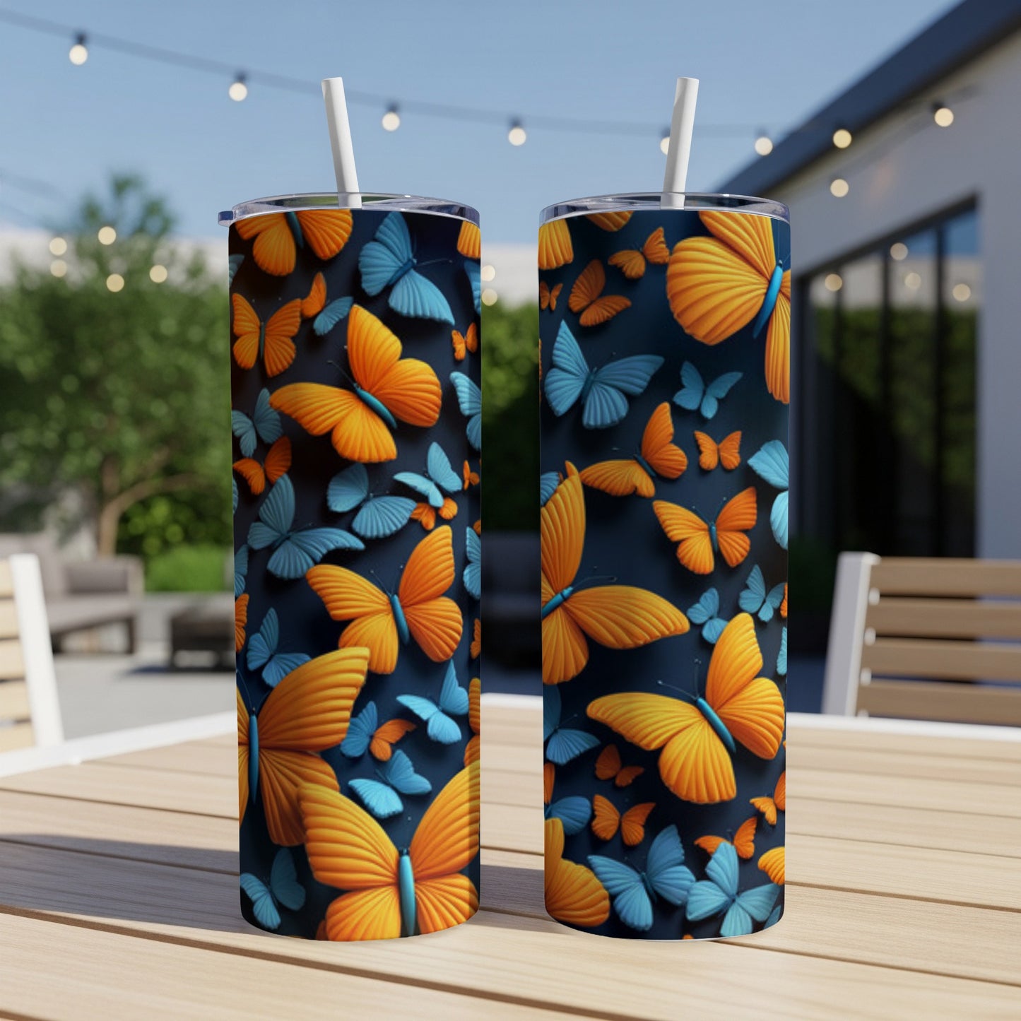 Two orange and blue butterfly tumblers with straws on a table outdoors.