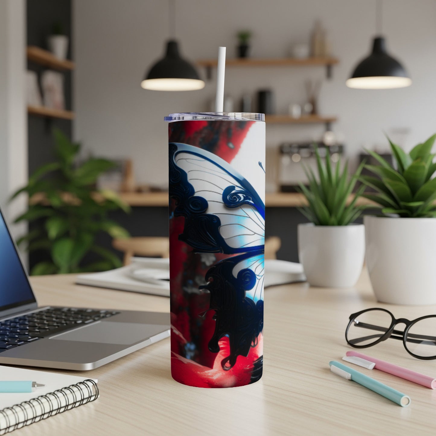 Tumbler with blue and white butterfly design, on a desk with laptop.