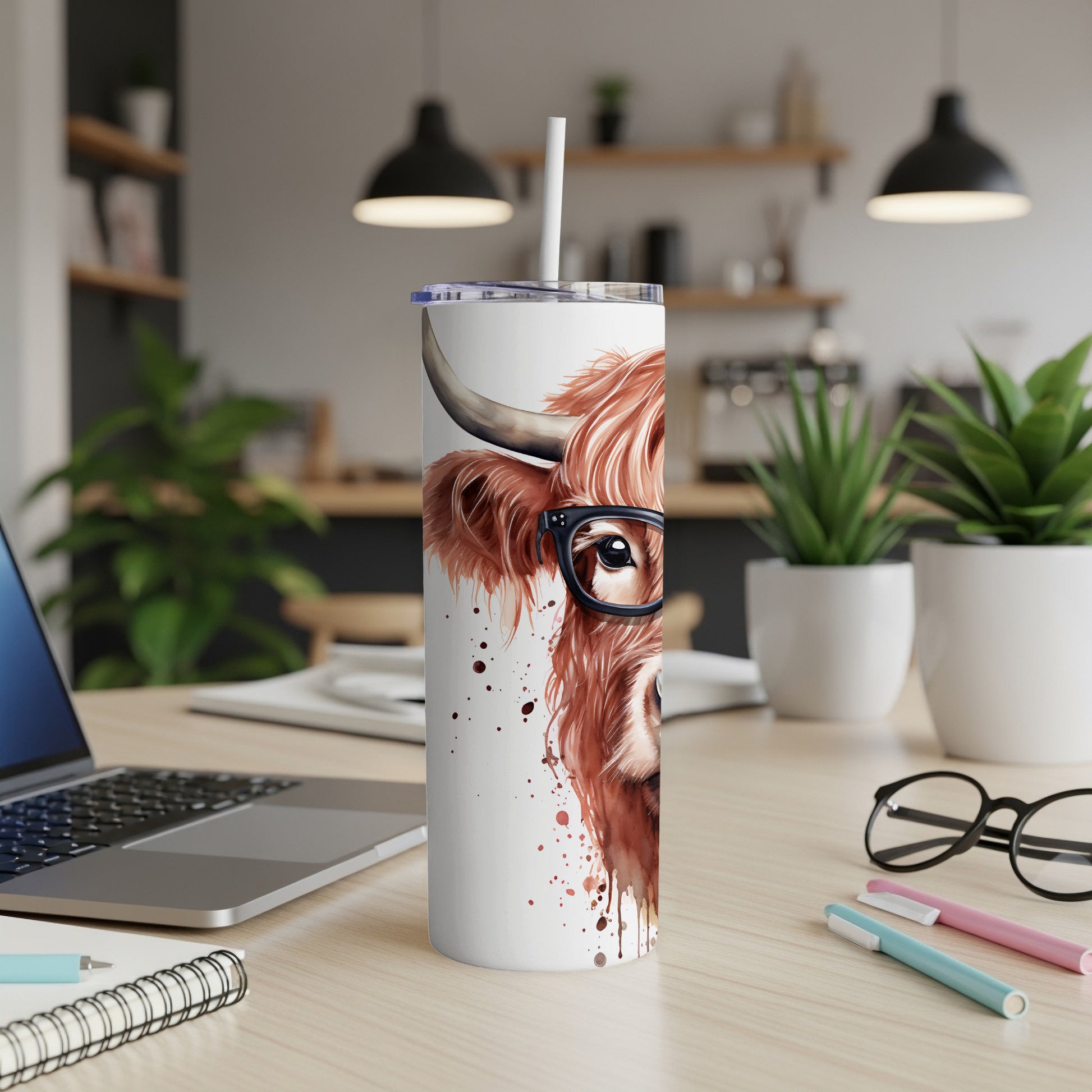 White tumbler with a Highland cow wearing glasses, against a blurred kitchen background.