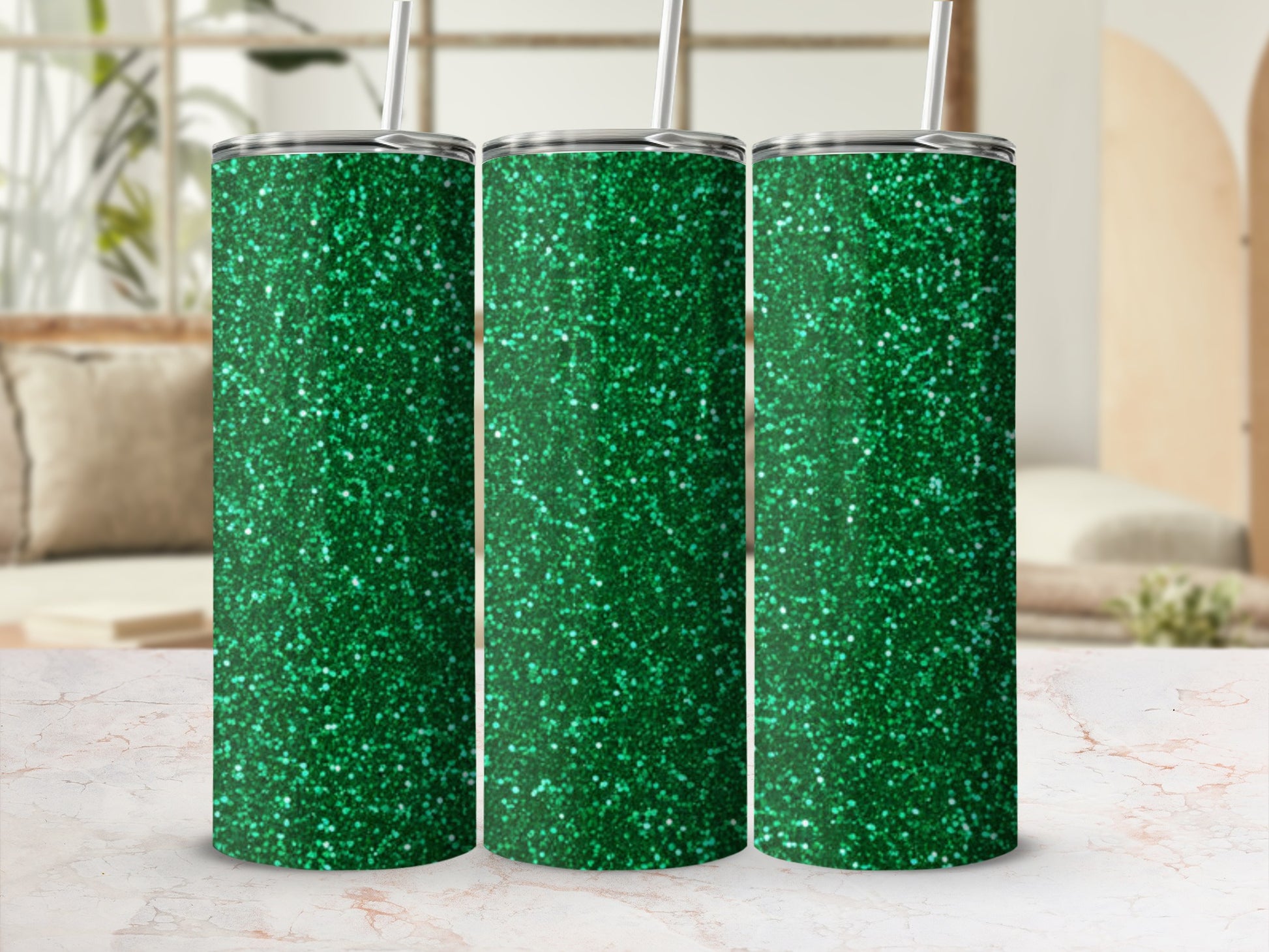 Three green glitter tumblers with straws stand on a marble surface.
