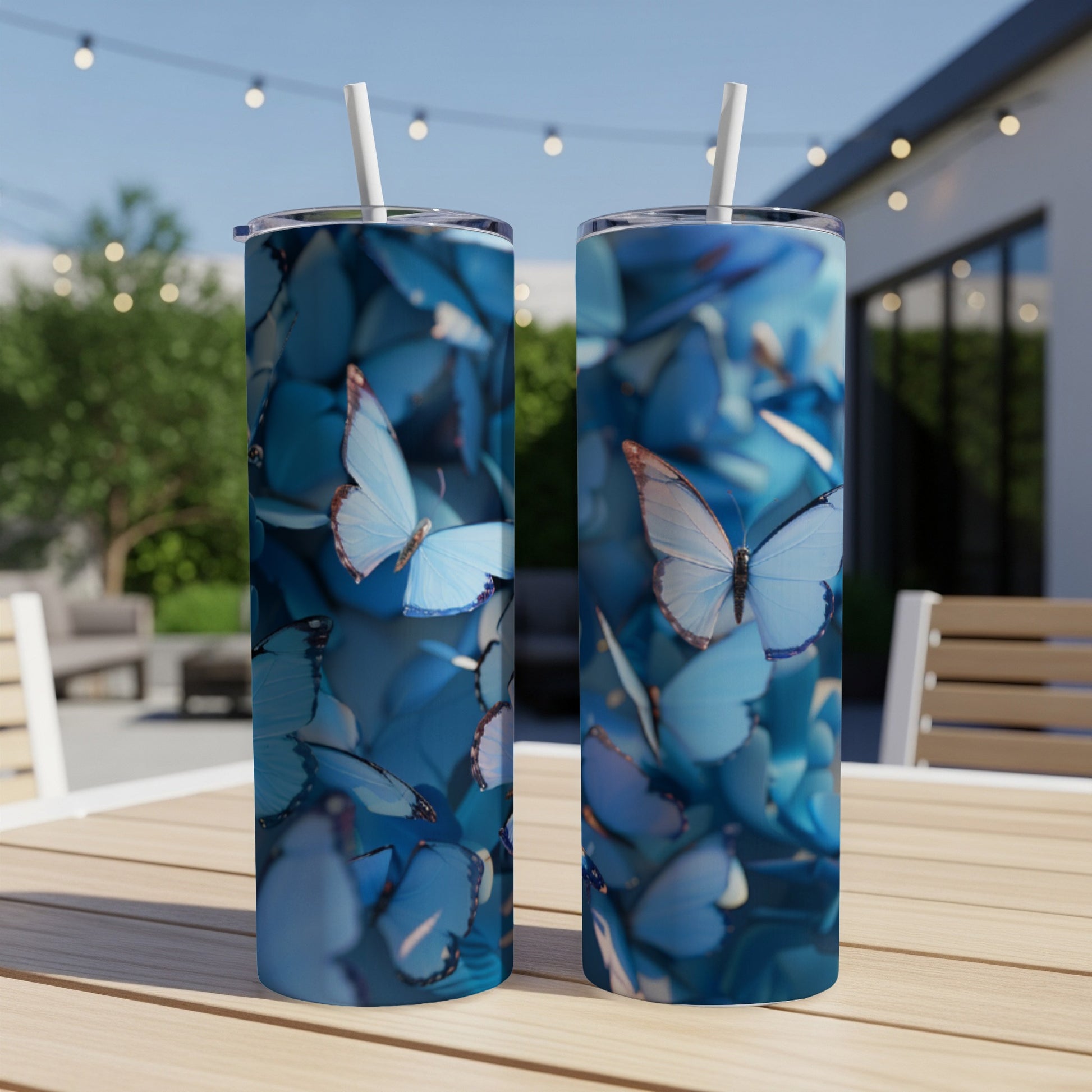 Two blue butterfly tumblers with straws on a wooden table.