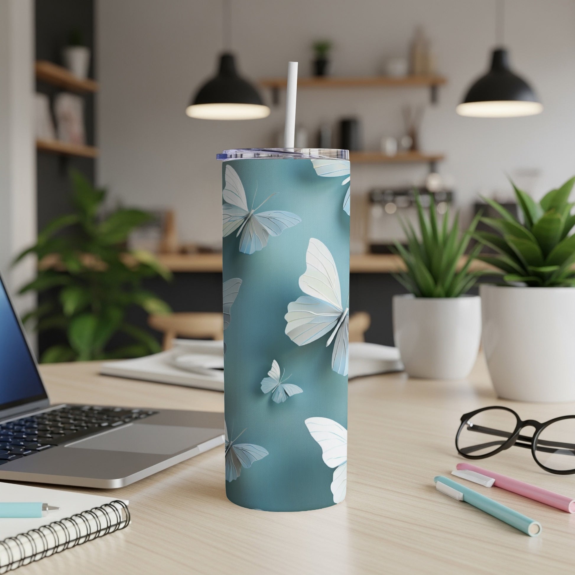 Blue tumbler with scattered light blue and white butterflies on a desk.