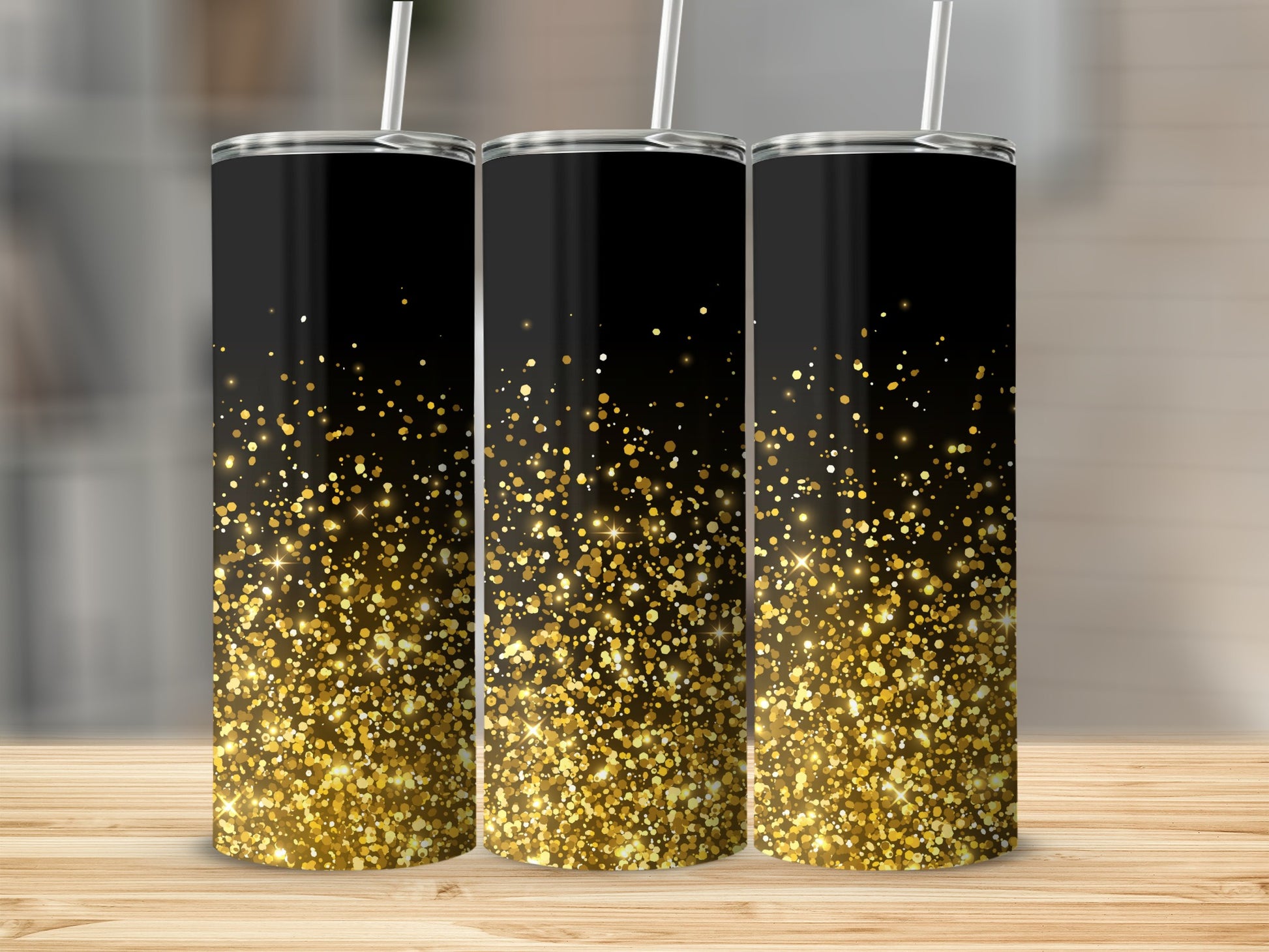 Three black tumblers with scattered gold glitter designs on a wooden surface.