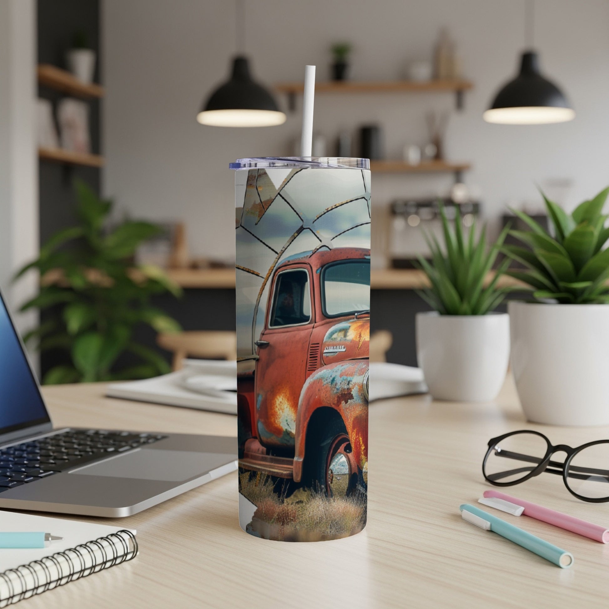 Rusty vintage truck on a tumbler next to a laptop and office supplies.