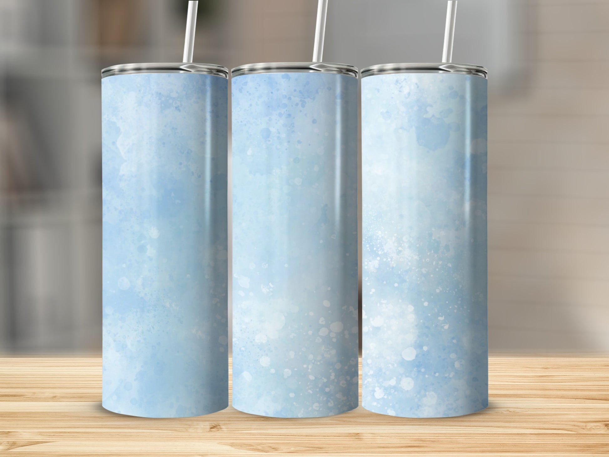 Three tumblers with light blue watercolor splatter design on wooden surface.
