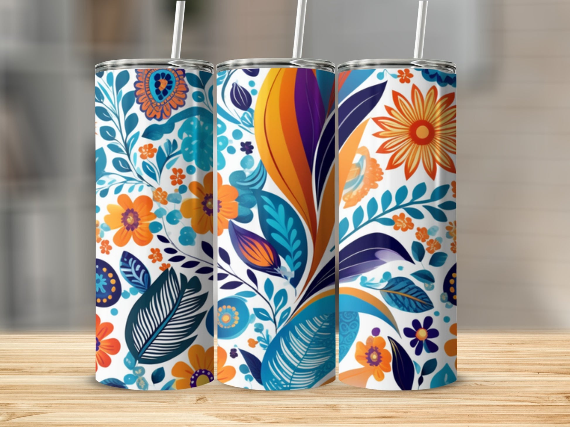 Three tumblers with colorful floral and leaf patterns on a wooden surface.