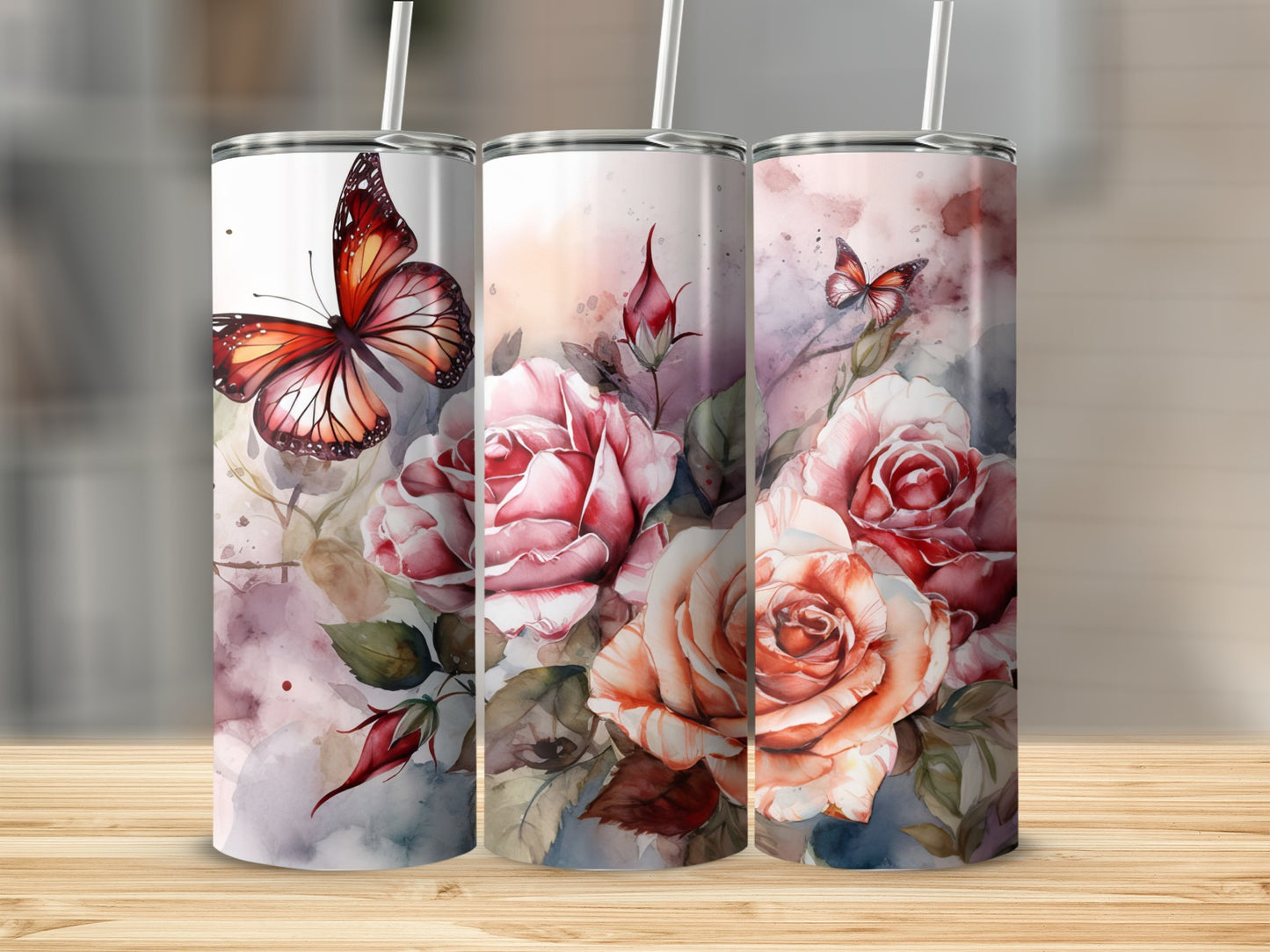 Three tumblers with pink roses and butterflies against a blurred watercolor background.