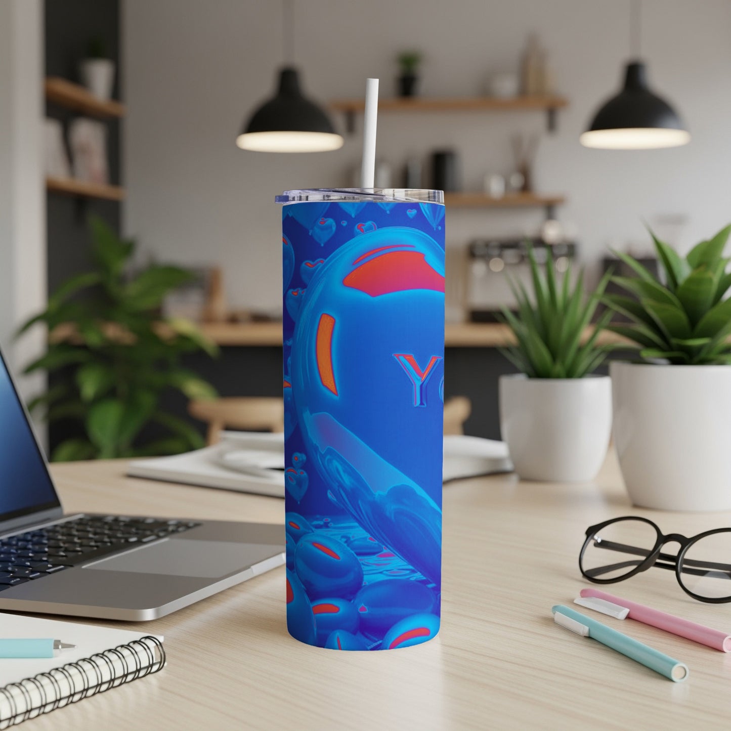 Blue tumbler with bright orange spheres and "Y" logo on a desk.