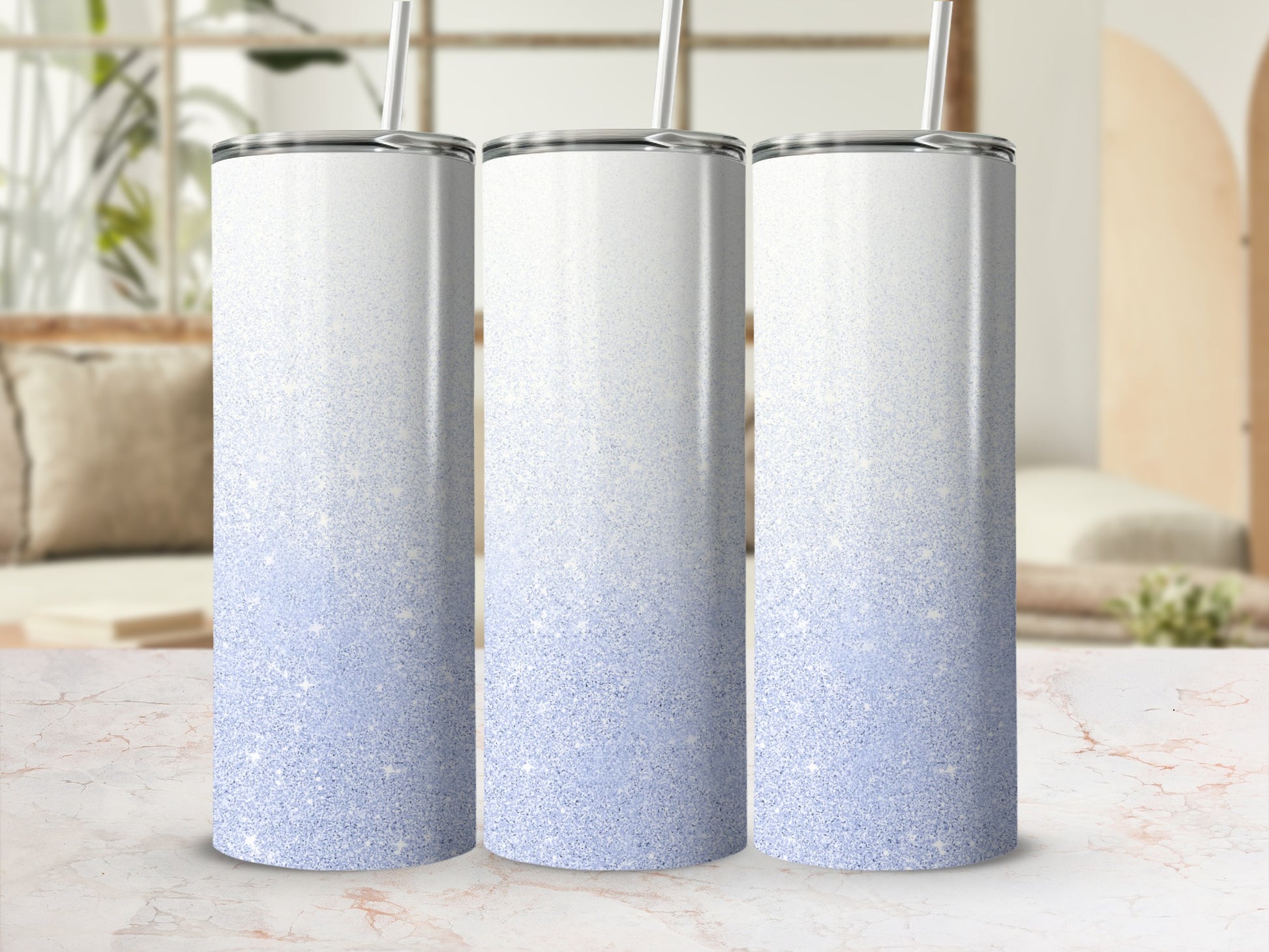 Three glittery blue ombre tumblers with straws stand side by side.