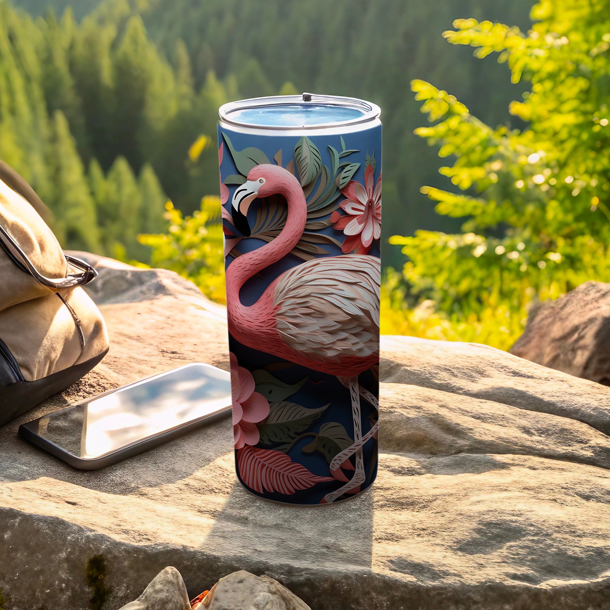 Pink flamingo and floral patterned insulated tumbler on rock.