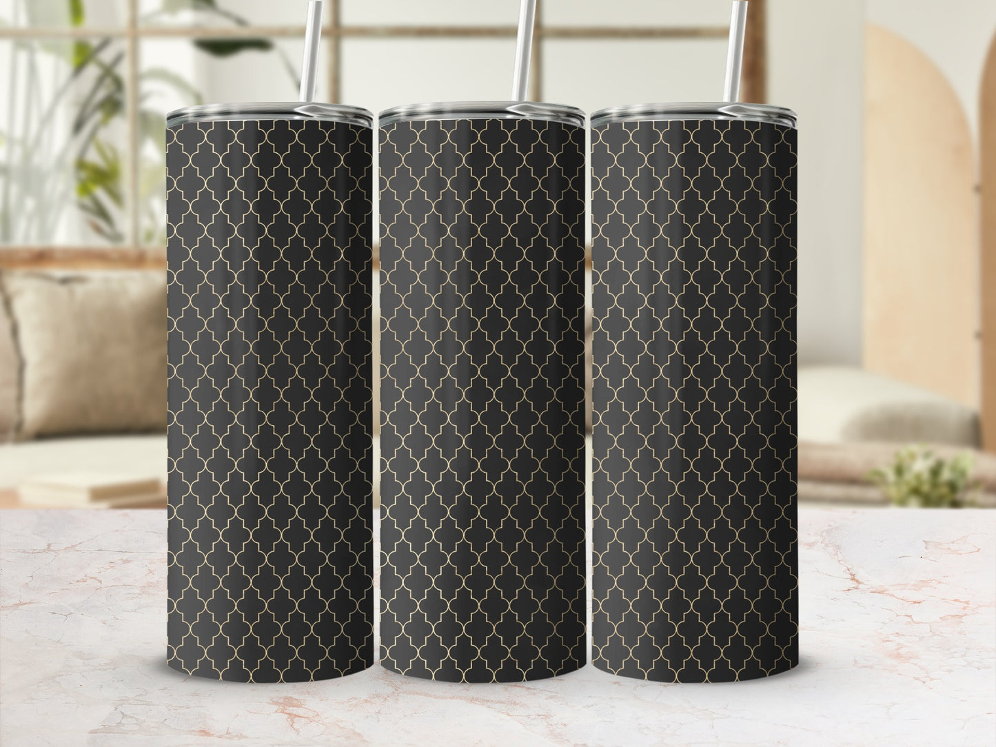 Three tumblers with black and gold quatrefoil pattern on a marble surface.