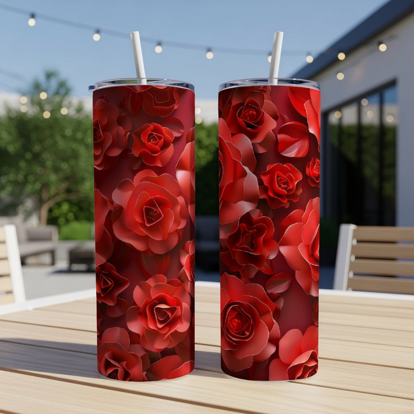 Two tall tumblers with red rose floral pattern on outdoor table.