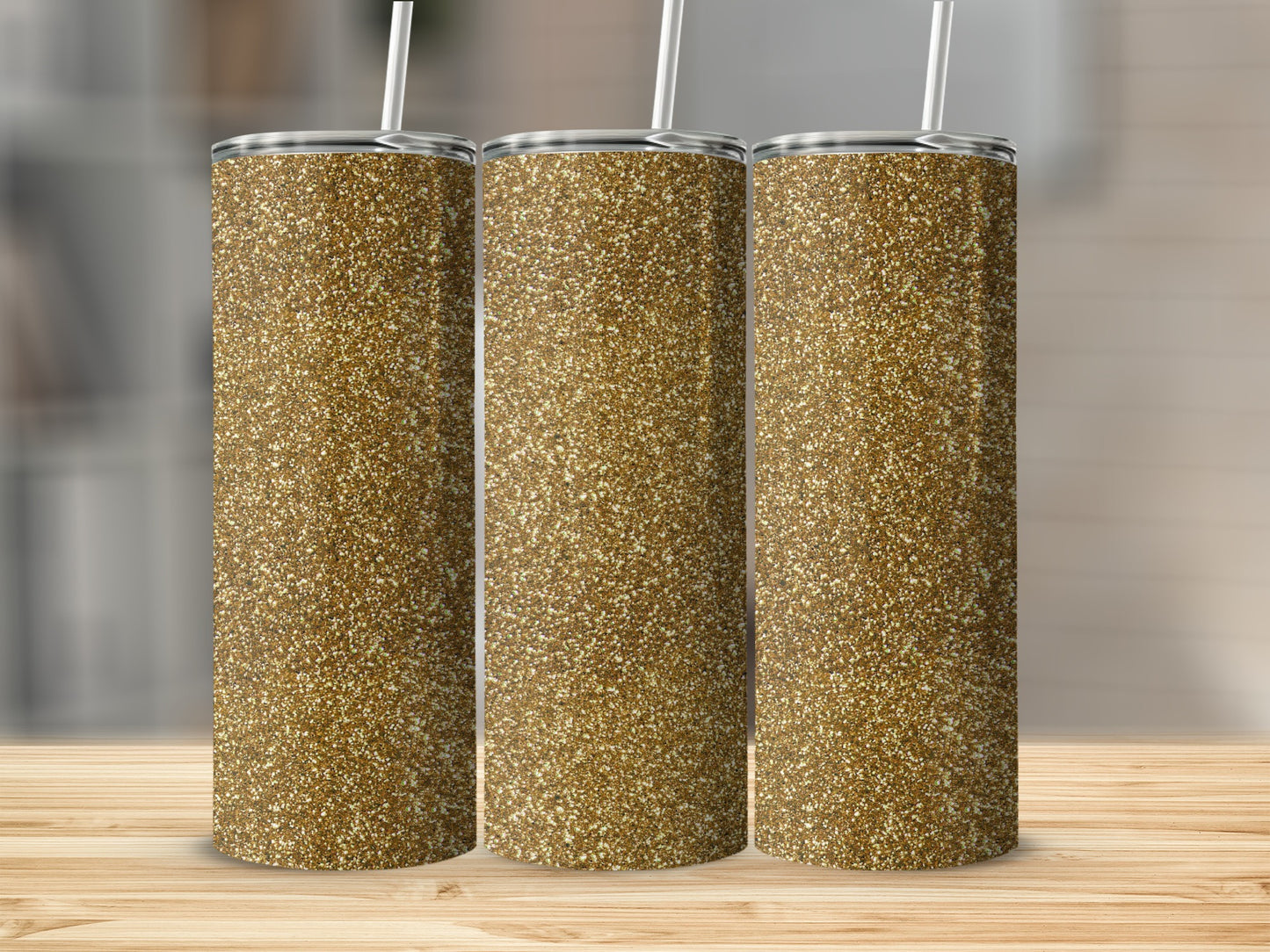 Three gold glitter tumblers with straws on a wooden surface.