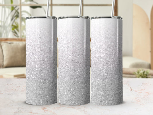 Three silver glitter tumblers with straws on a marble surface.