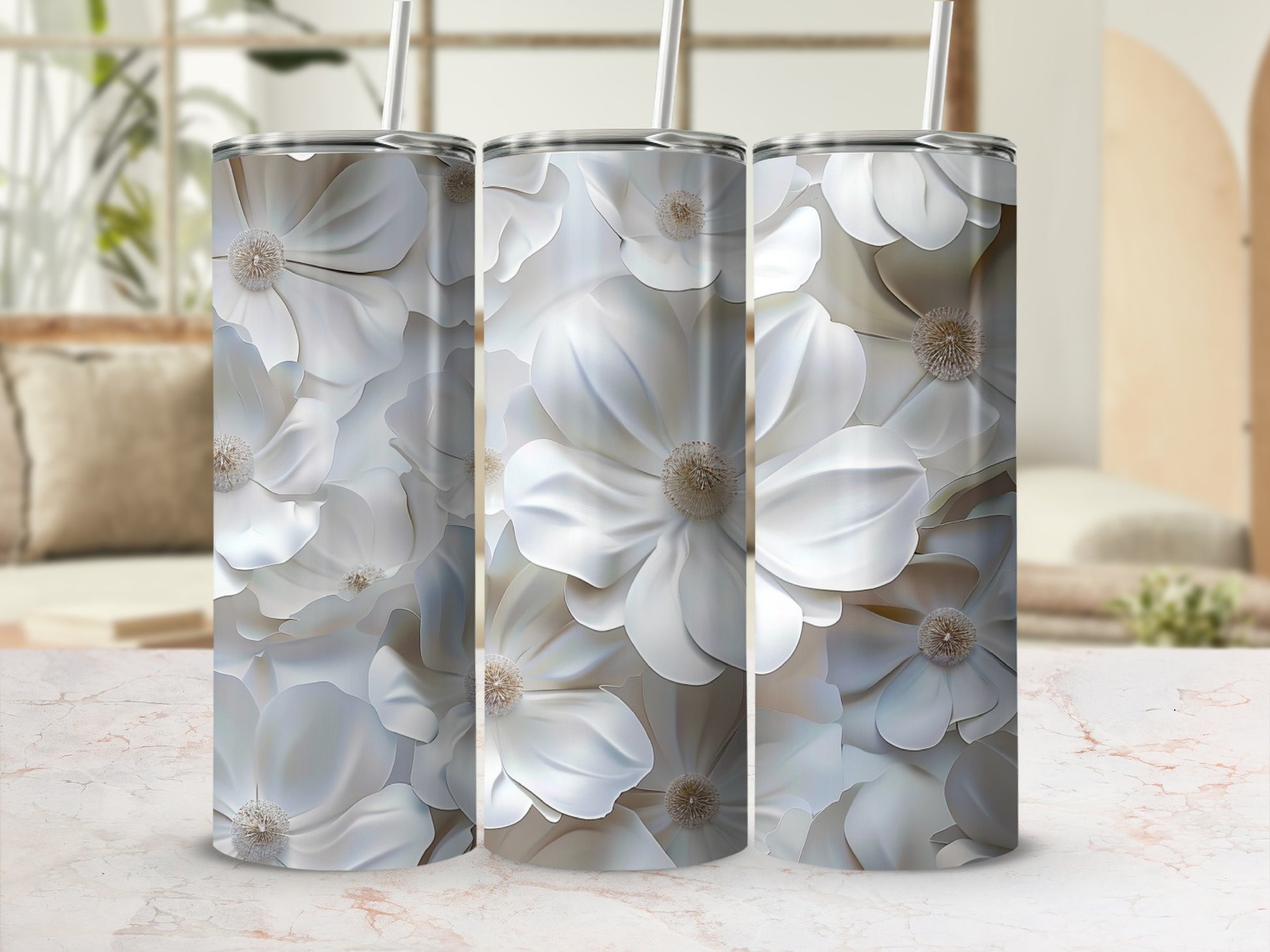 Three white floral tumblers with straws against a blurred background.