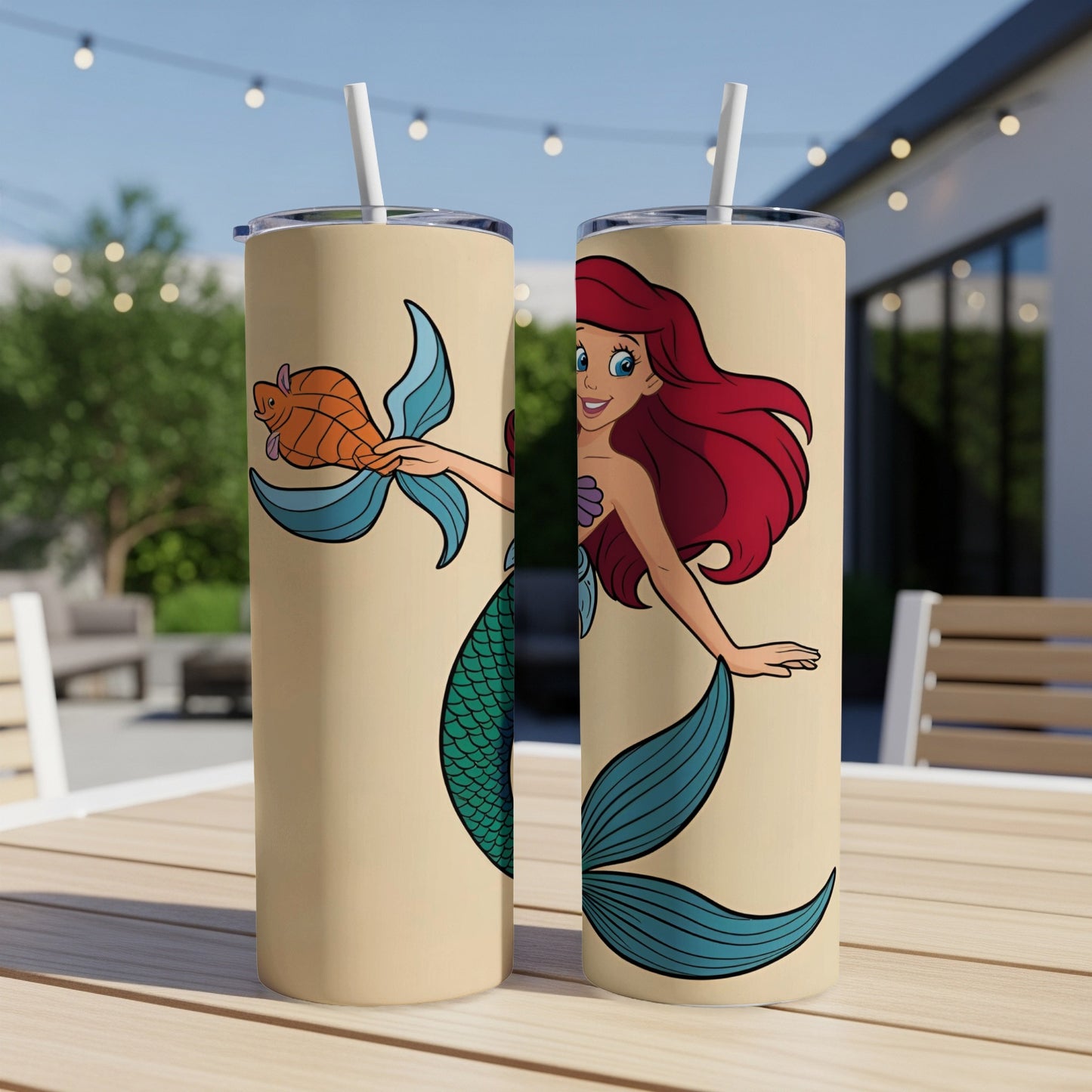 Two tan tumblers featuring Ariel the mermaid holding a fish, against a blurred outdoor background.