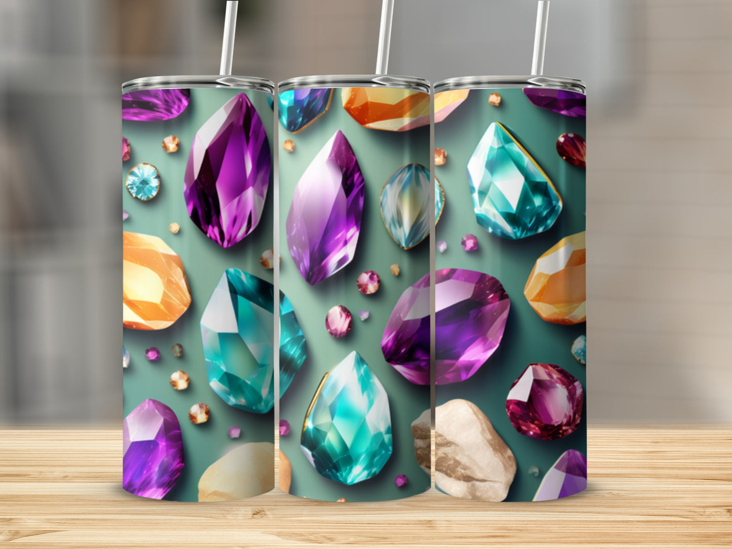 Three tumblers with colorful gemstone designs arranged on a wooden surface.