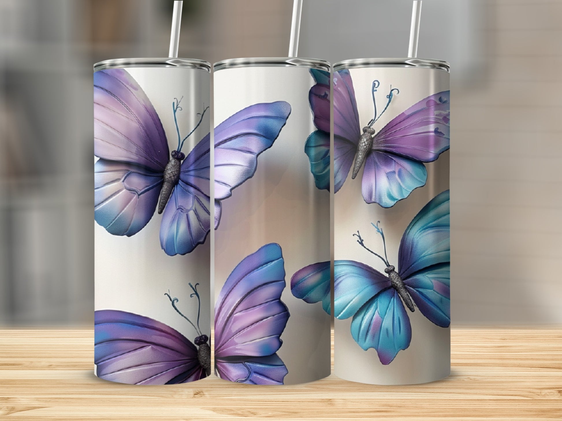 Two tall tumblers with purple and blue butterfly designs on a wooden surface.