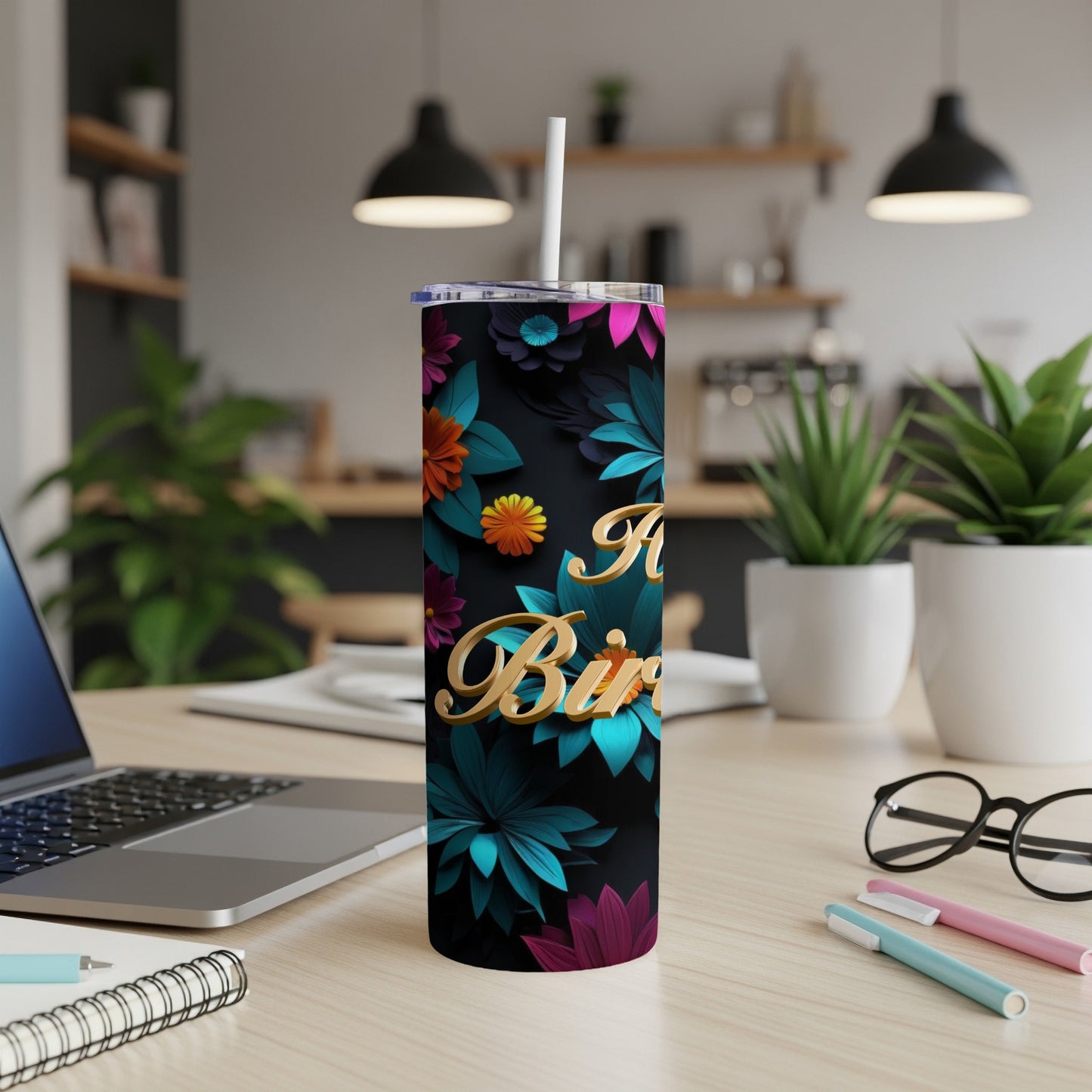 Gold 3D lettering on a black tumbler with floral design, straw inserted.