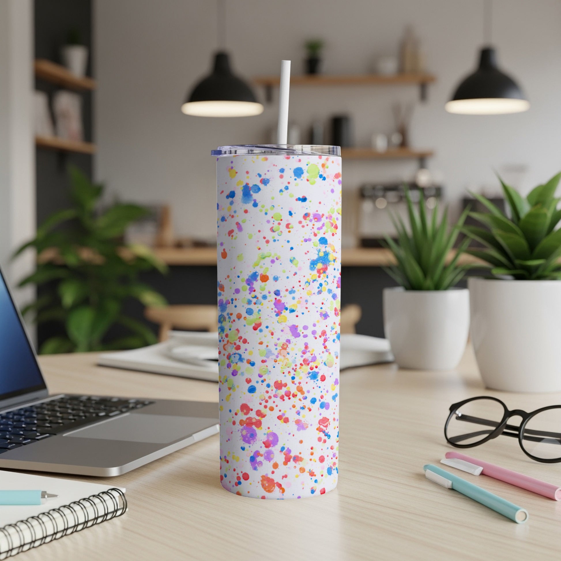 White tumbler with colorful paint splatter pattern and straw.