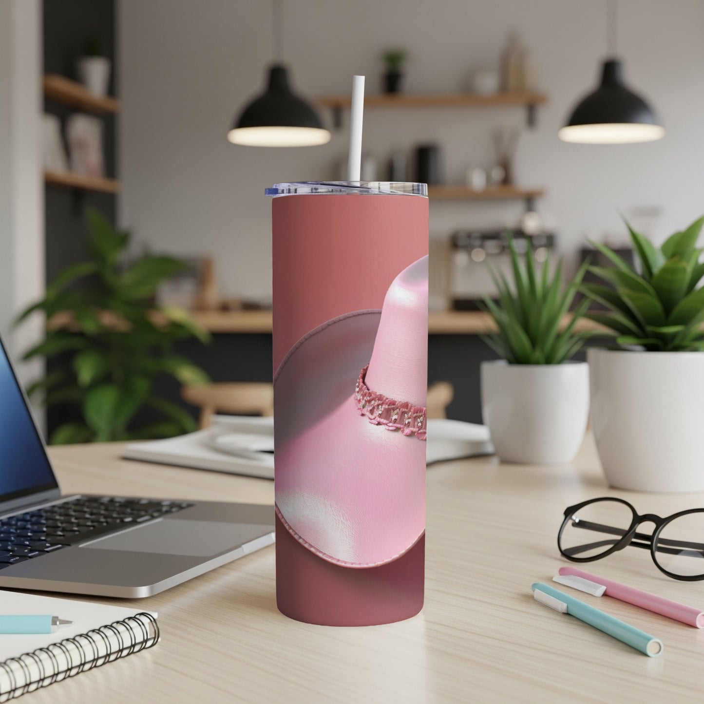 Pink cowboy hat tumbler with beaded band on desk.