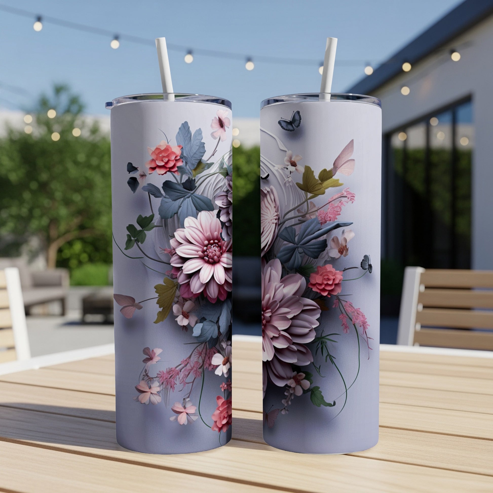 Two tall, narrow tumblers with floral designs and straws, resting on a wooden table.