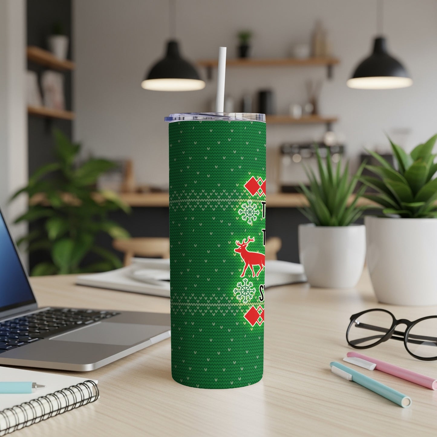 Green tumbler with a festive holiday sweater pattern and a reindeer graphic.