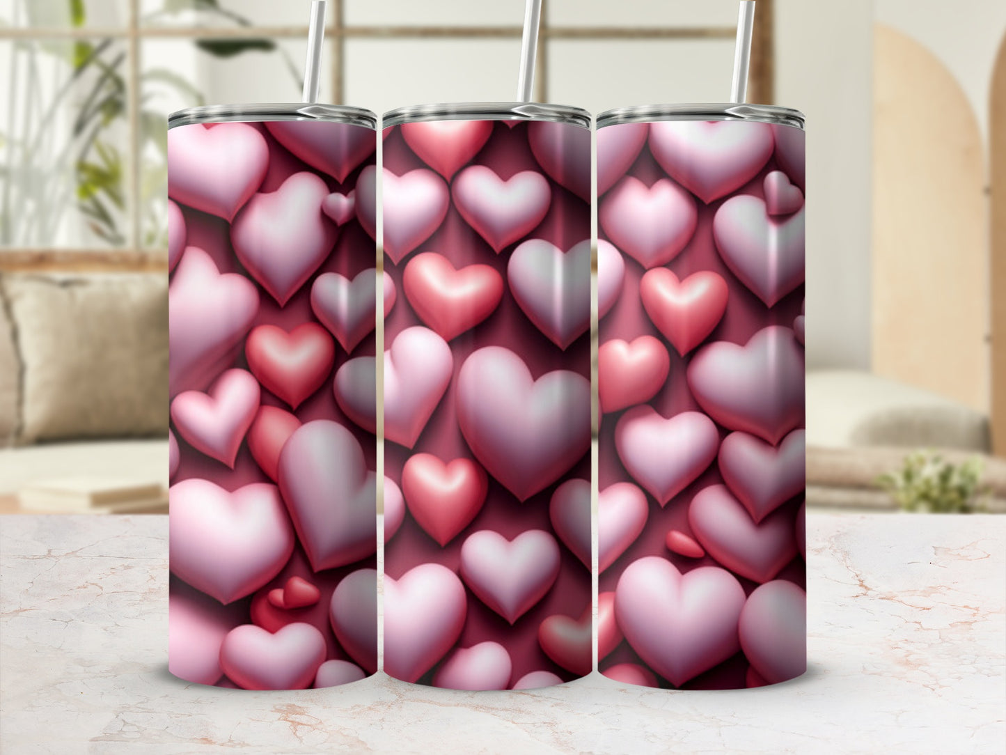 Three pink heart-patterned tumblers with straws, against a blurred background.