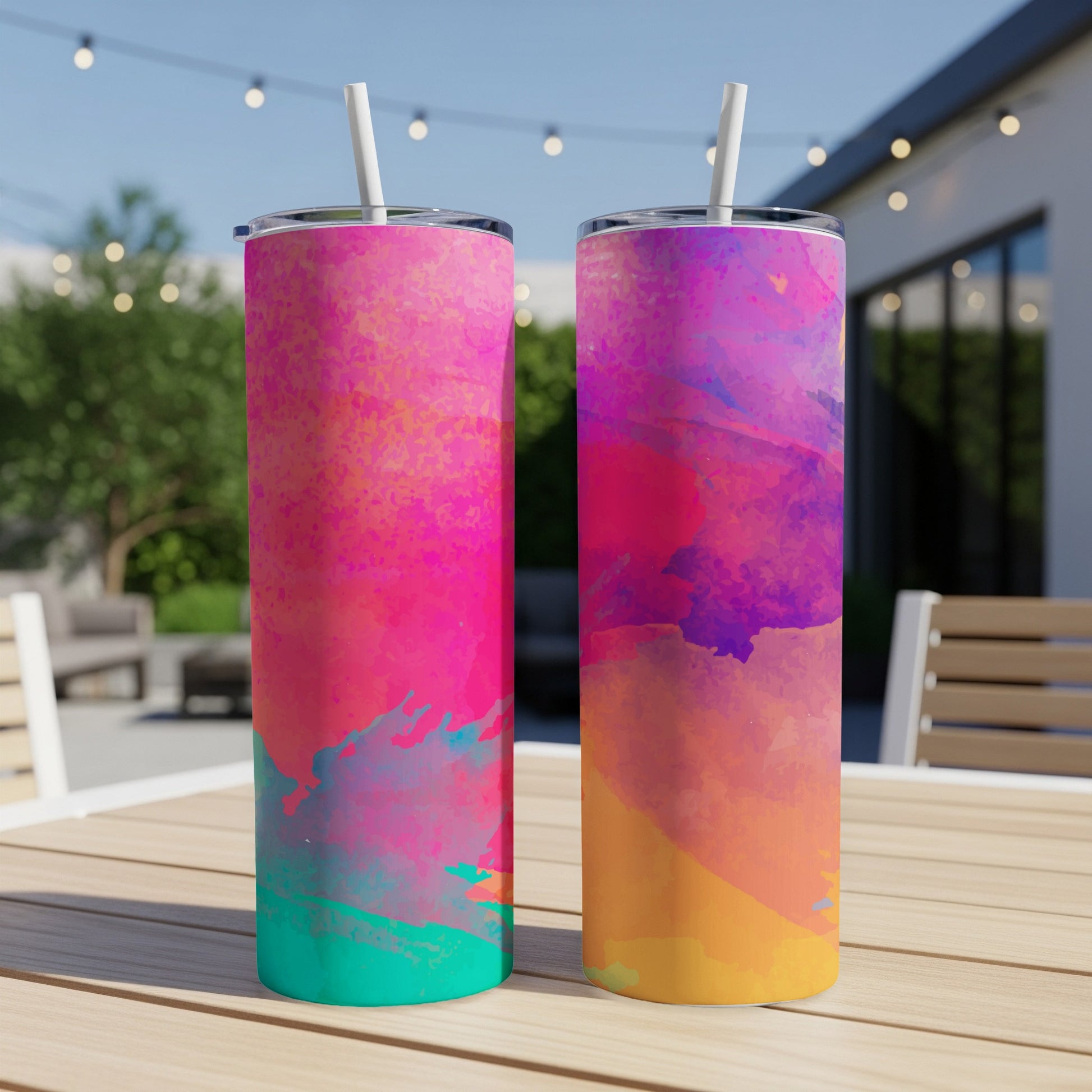 Two tall tumblers with colorful abstract paint splatter patterns on a wooden table.