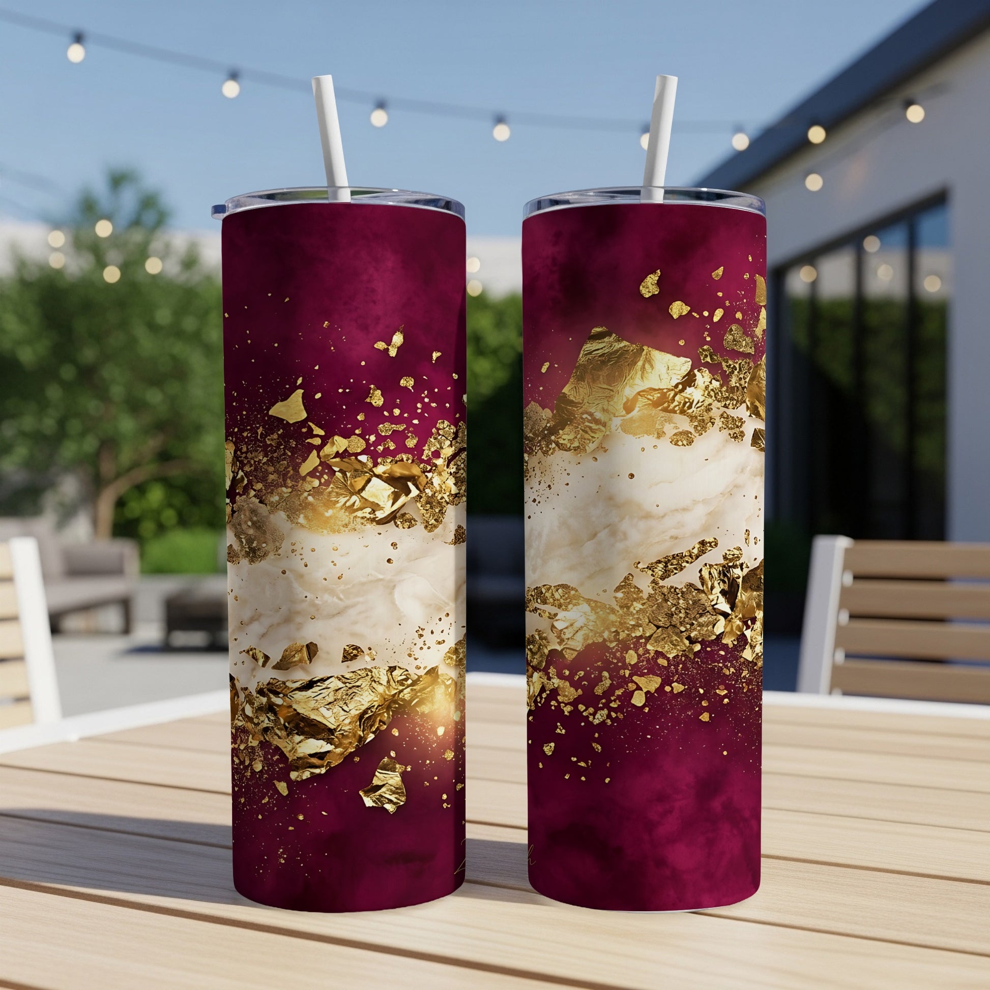 Two tumblers with burgundy and gold marbled design on an outdoor table.