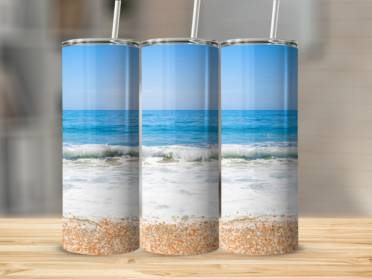 Three tumblers featuring a beach scene with ocean waves and sand.