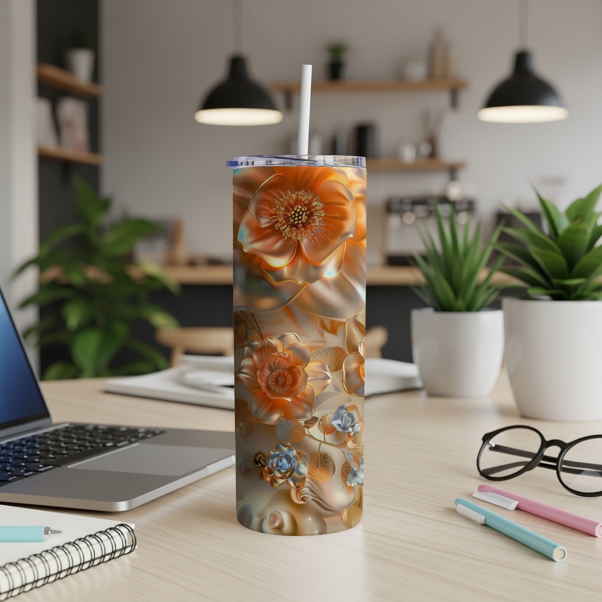 Orange and blue floral tumbler with straw on desk.