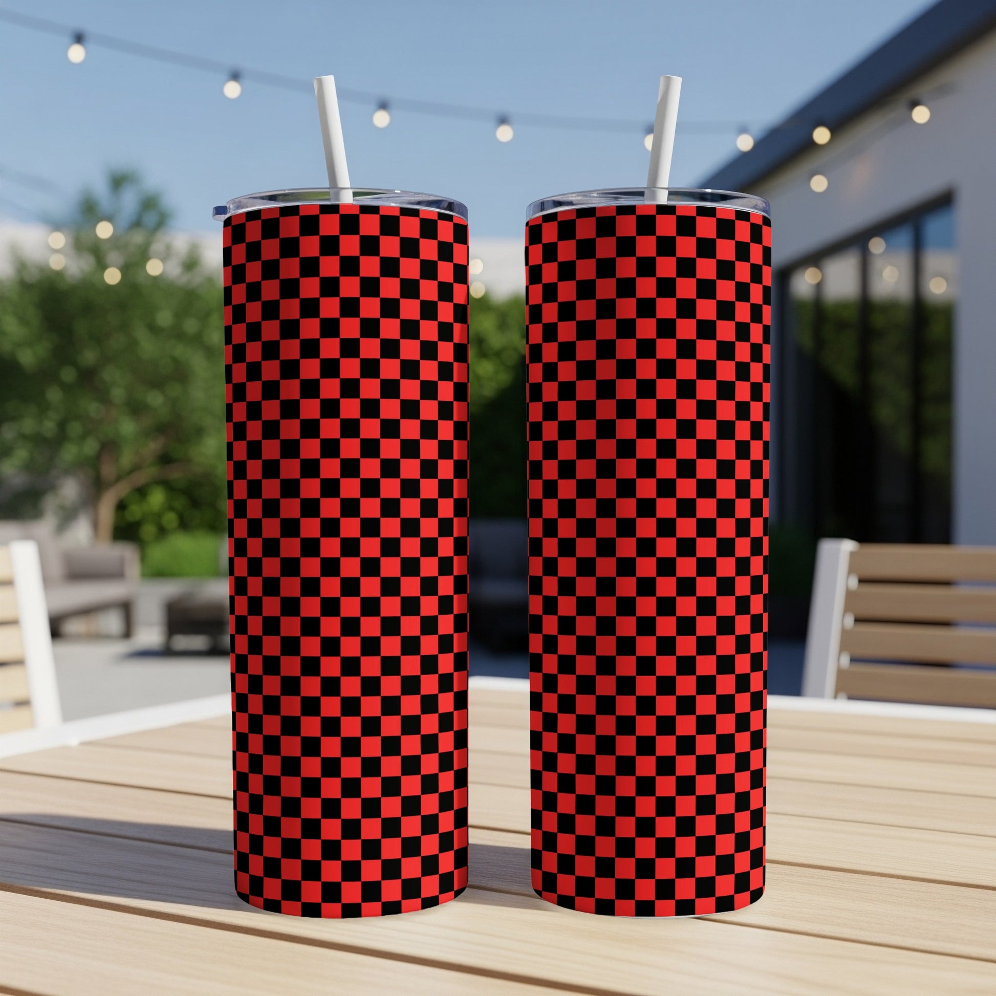 Two red and black checkered tumblers with straws on a table.