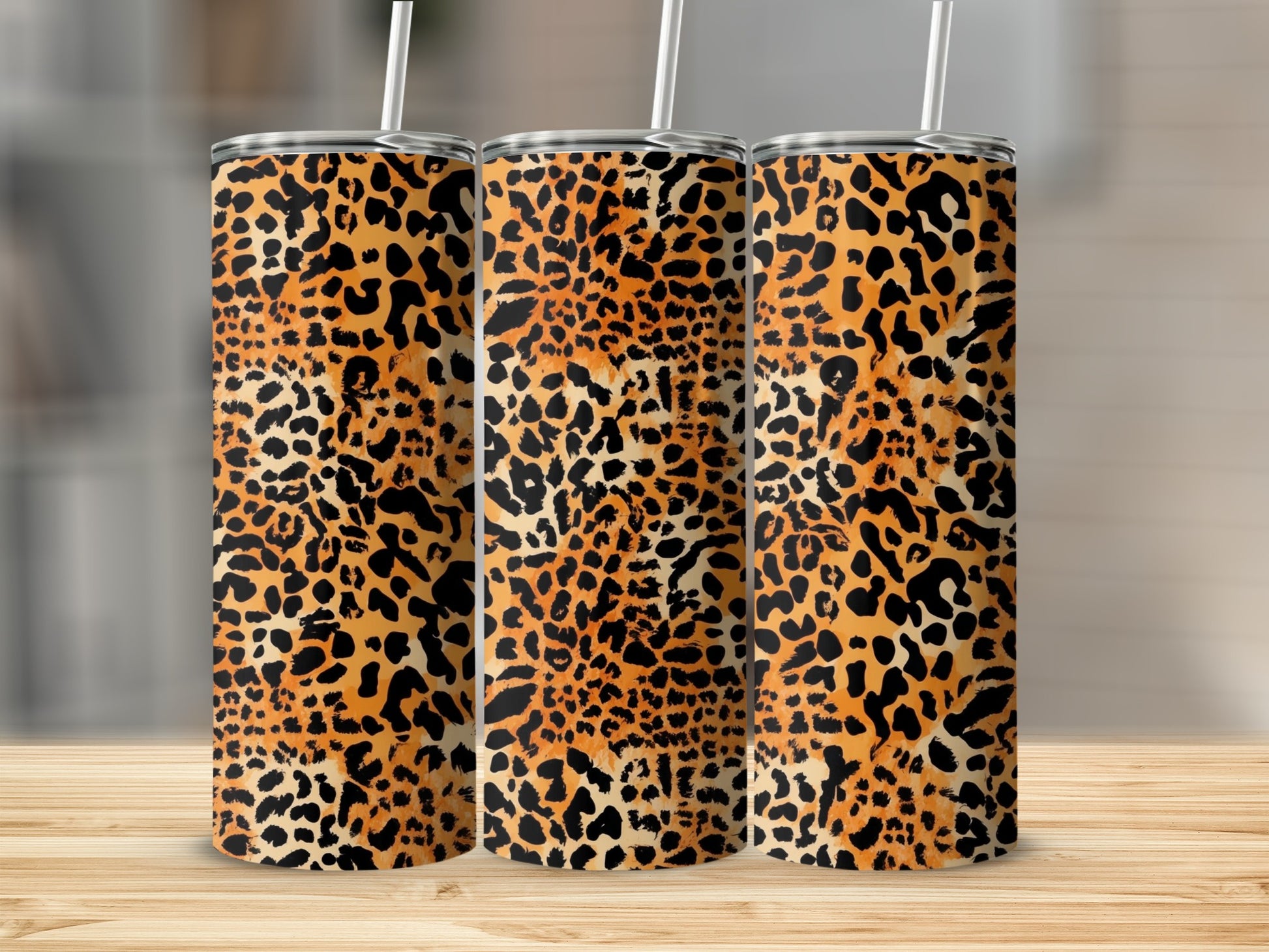 Three tumblers with leopard print patterns on a wooden surface.
