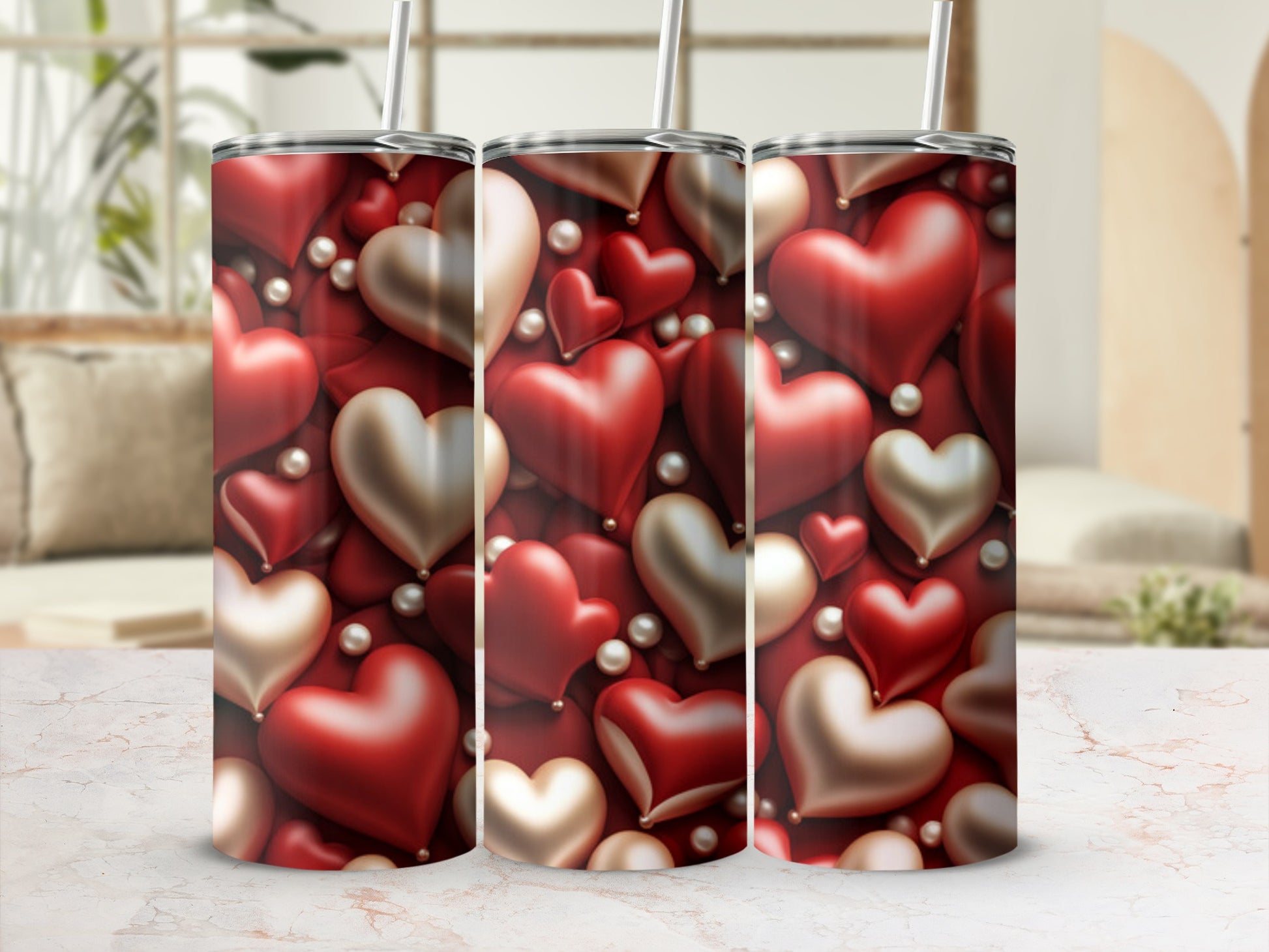 Three metallic heart pattern tumblers with straws on a marble surface.