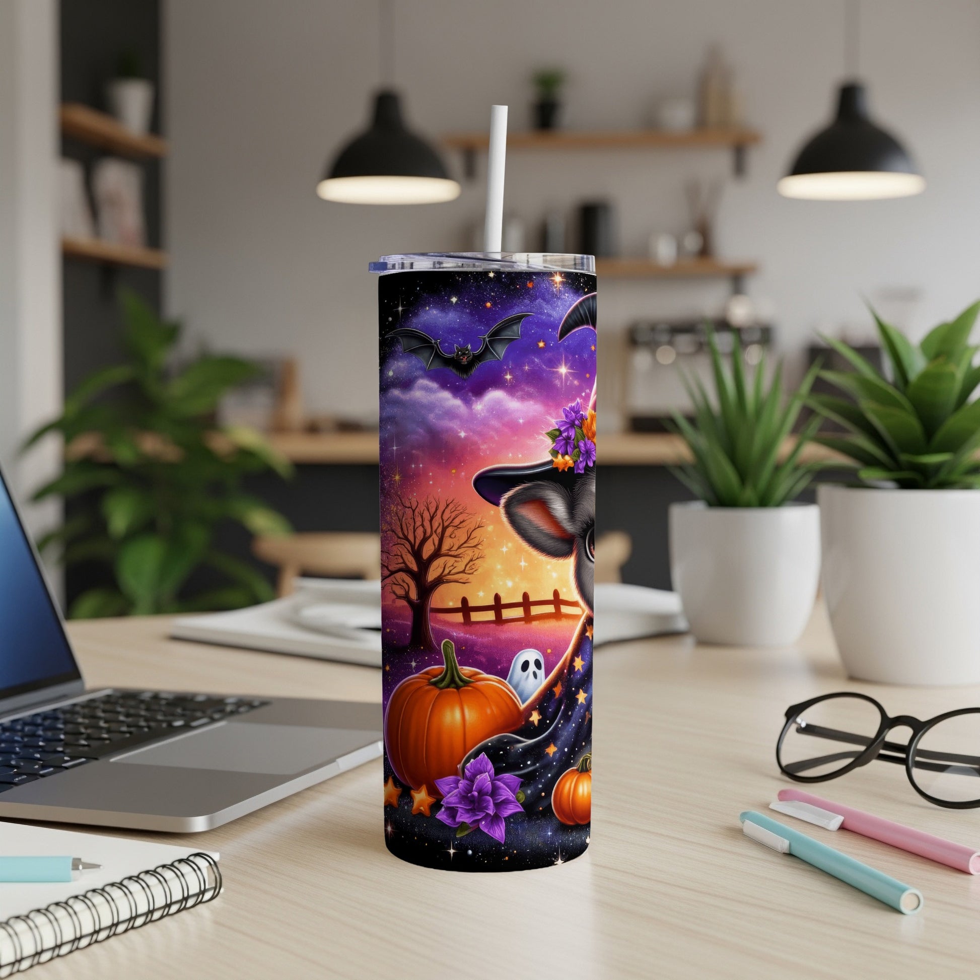 Halloween tumbler with spooky cat, pumpkin, and stars on a desk.