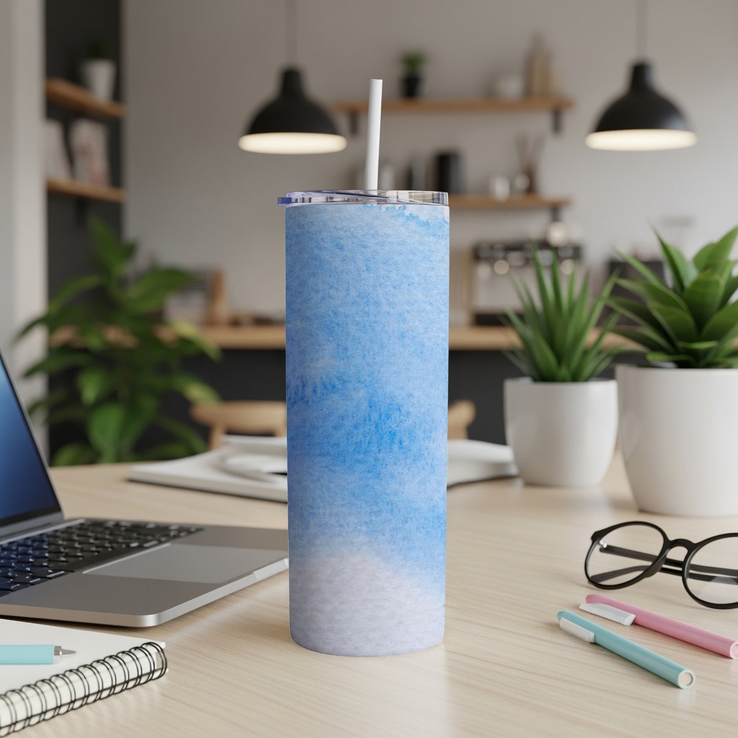 Blue and white marbled tumbler with straw on a desk.