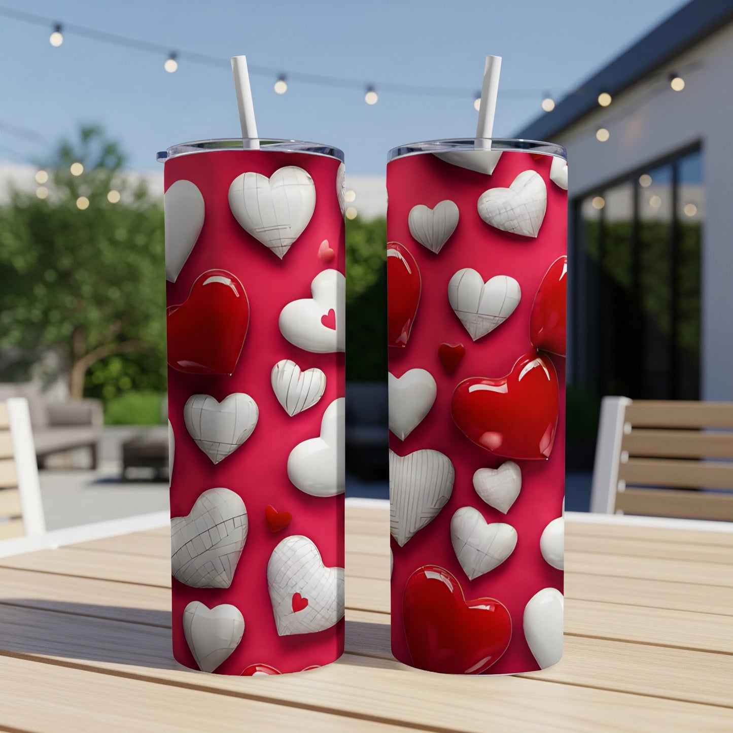 Two red tumblers with a white and red heart pattern on a patio table.