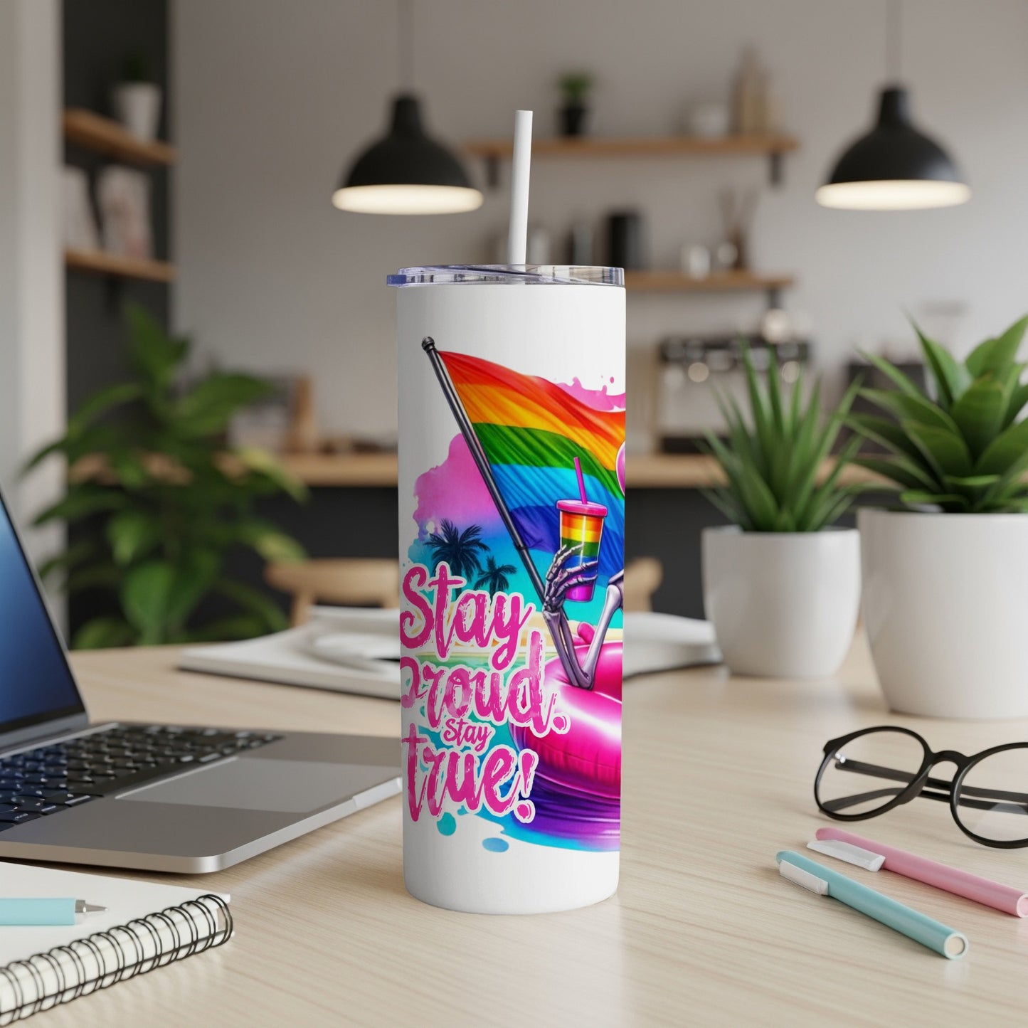 Pride flag tumbler with "Stay Proud, Stay True" text, on a desk.