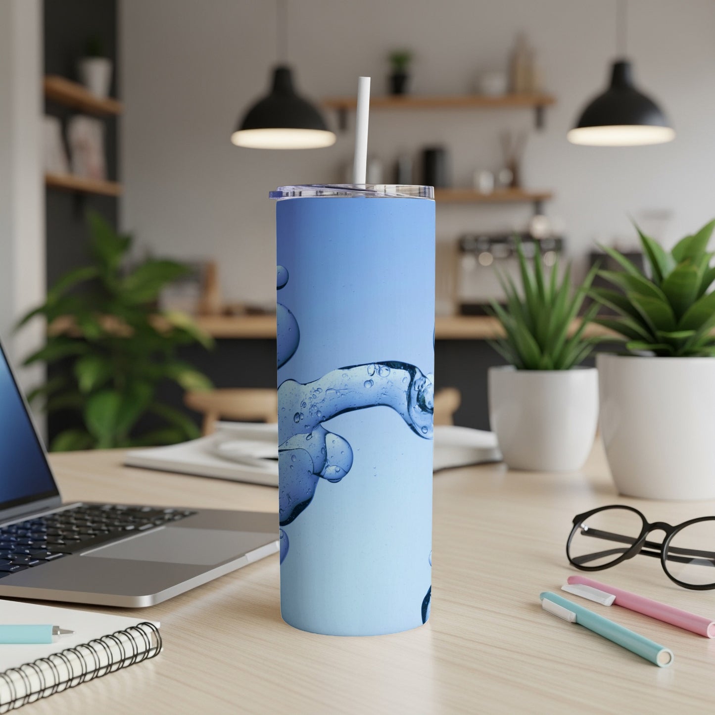 Blue tumbler with swirling water effect, on a desk with laptop.