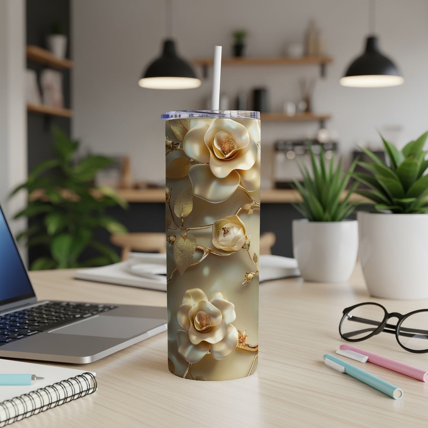 Gold floral tumbler with white straw on a desk.