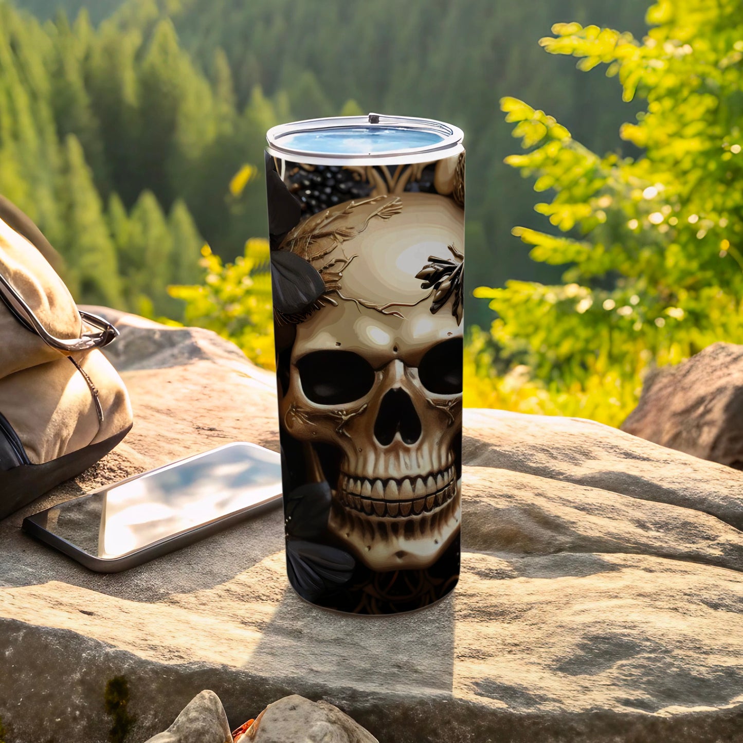 Skull design on a black tumbler with a backpack and phone outdoors.