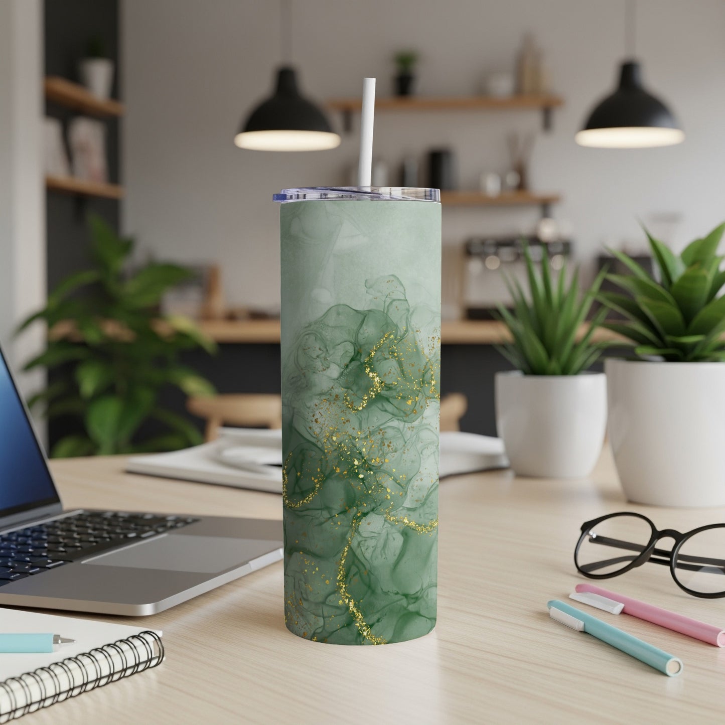 Green marble tumbler with gold glitter accents on a wooden desk.