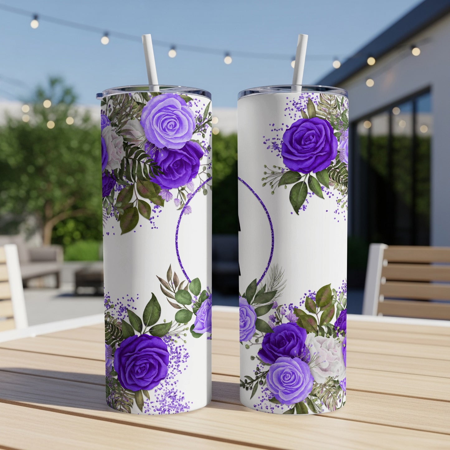 Two white tumblers with purple floral designs sit on a wooden table outdoors.