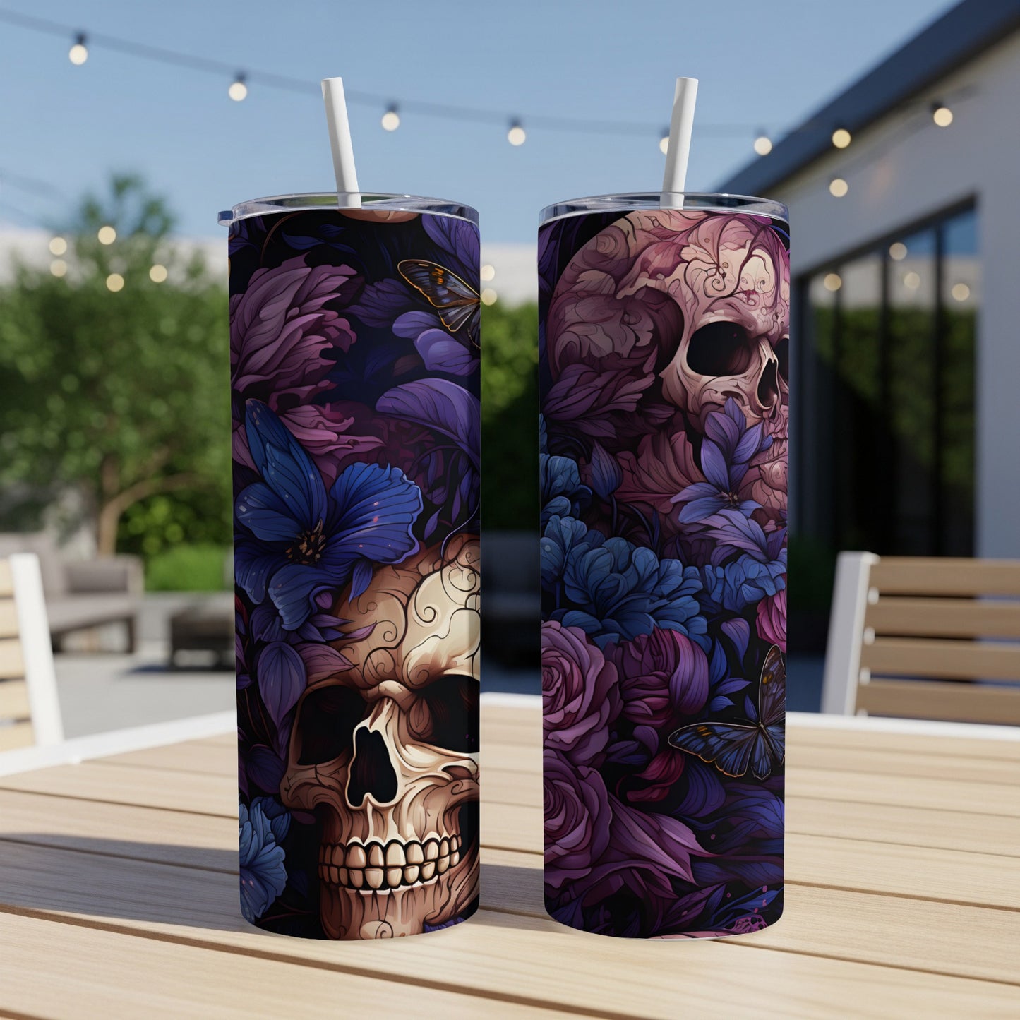 Two tumblers with skull and floral designs sit on a wooden table outdoors.