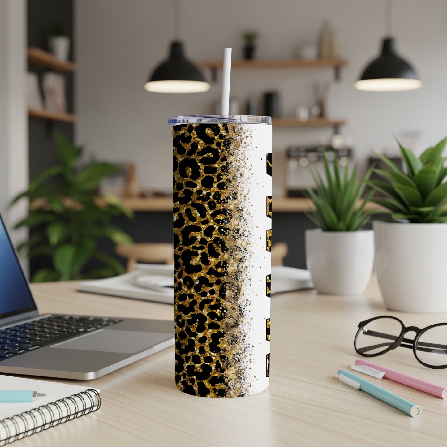 Leopard print tumbler with straw on a desk next to a laptop.