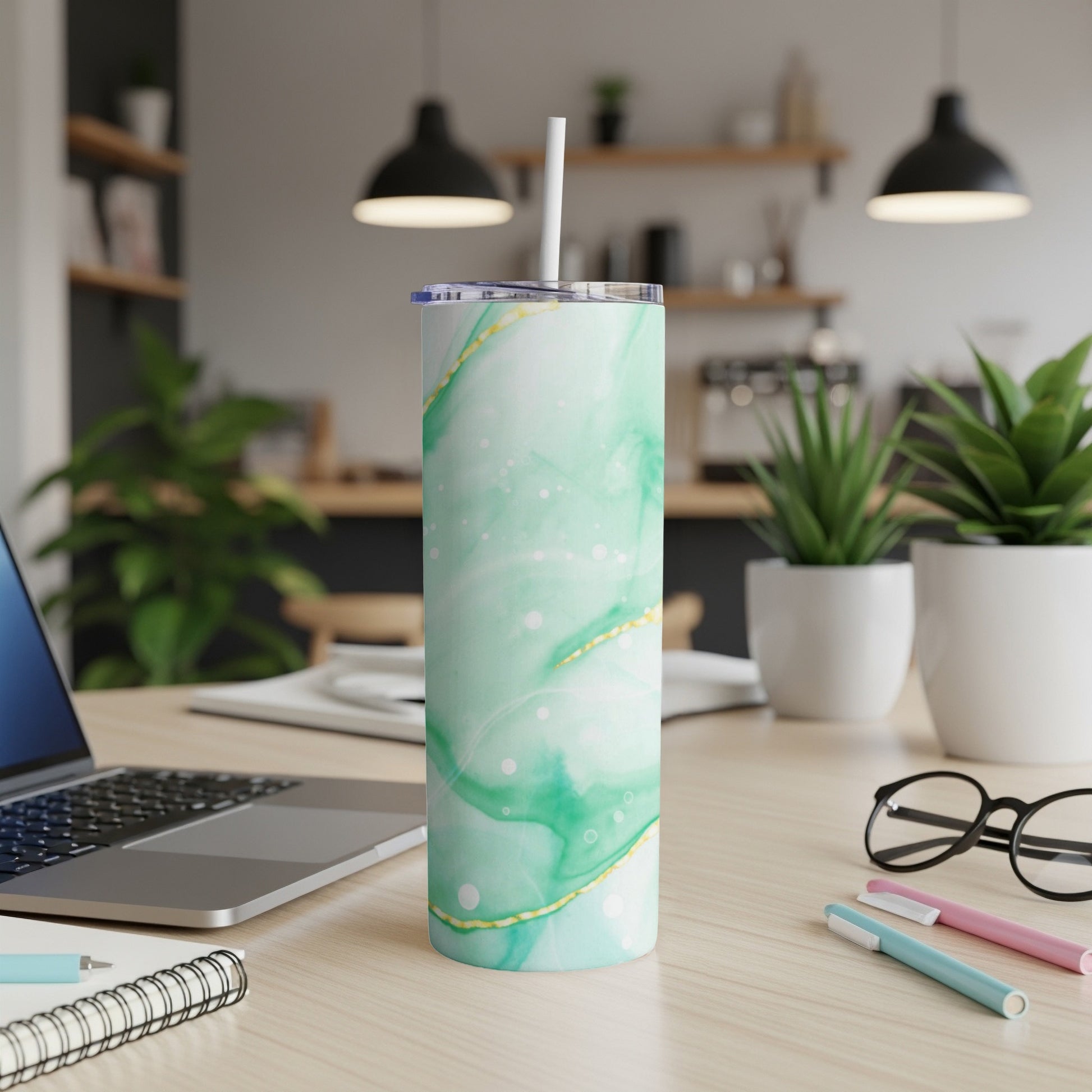 Green and white marbled tumbler with gold accents on a desk.